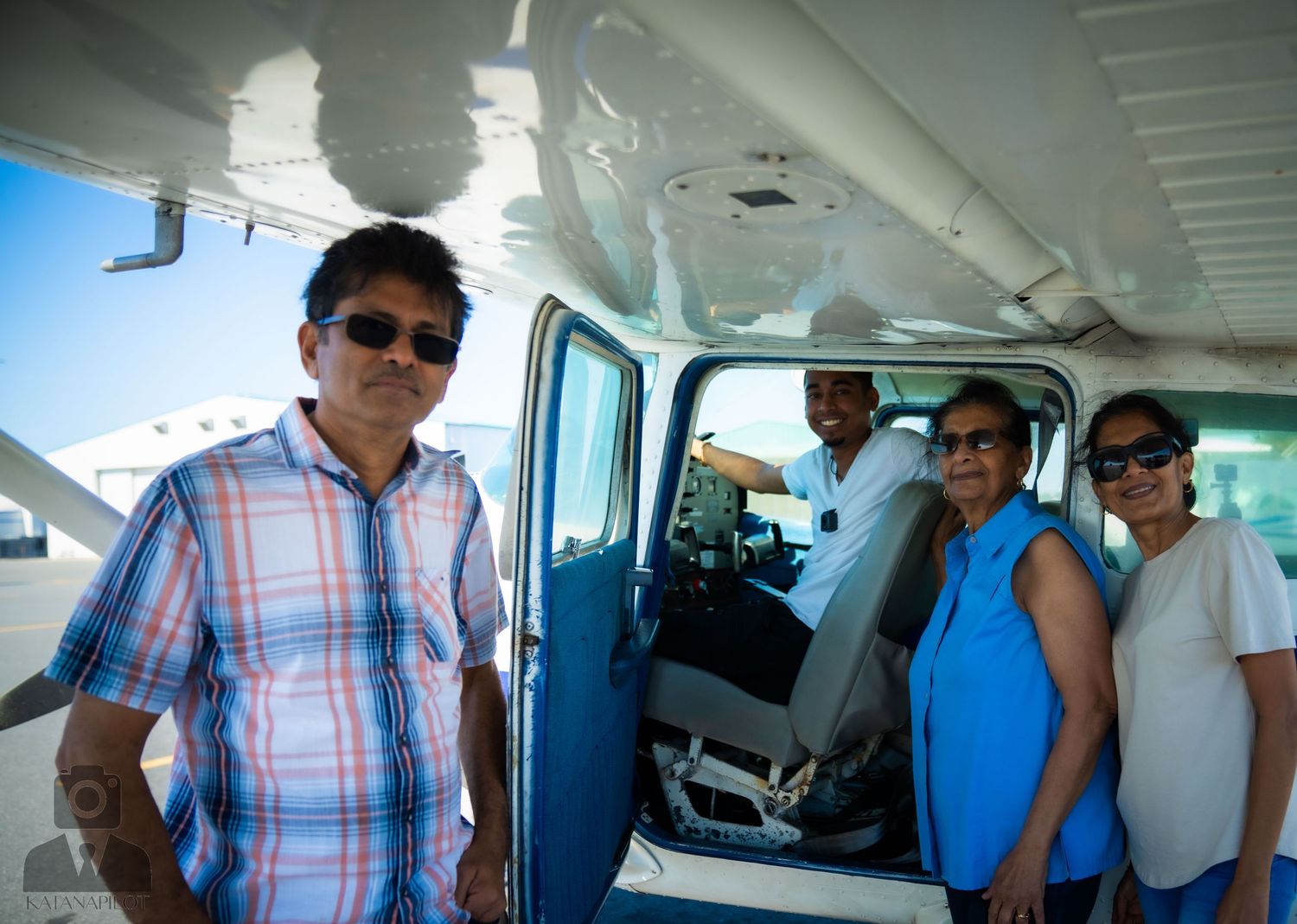 People boarding a small private aircraft on a sunny day at an airfield.
