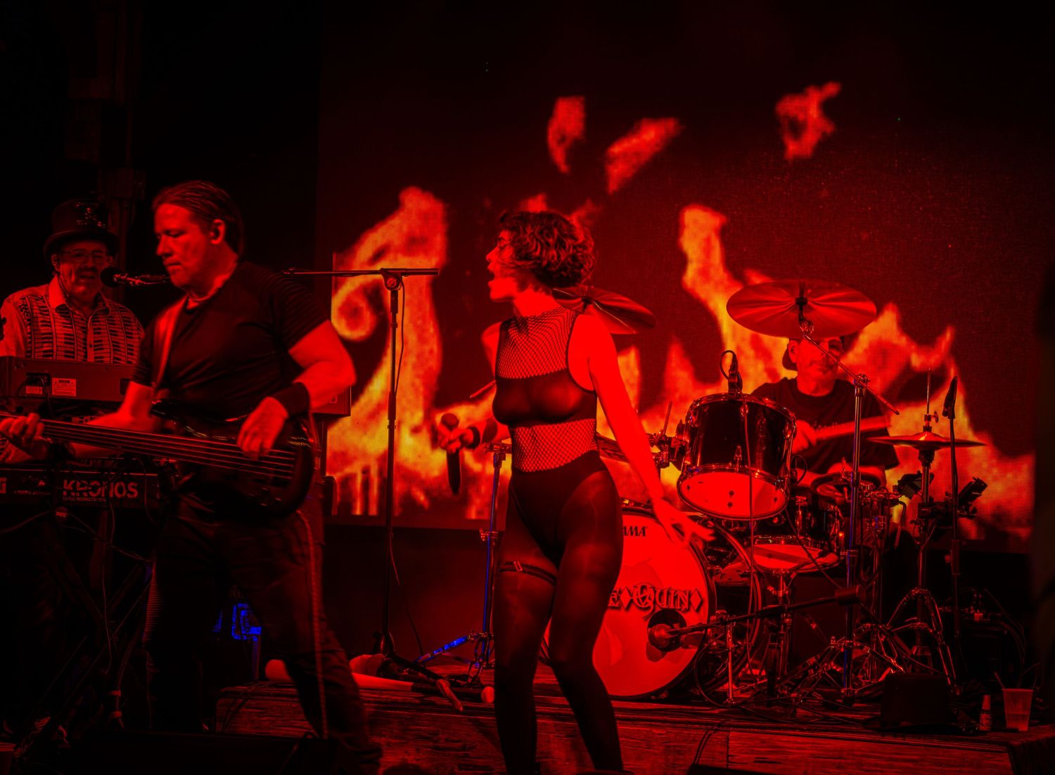 Rock concert scene with musicians performing under dramatic red stage lights.