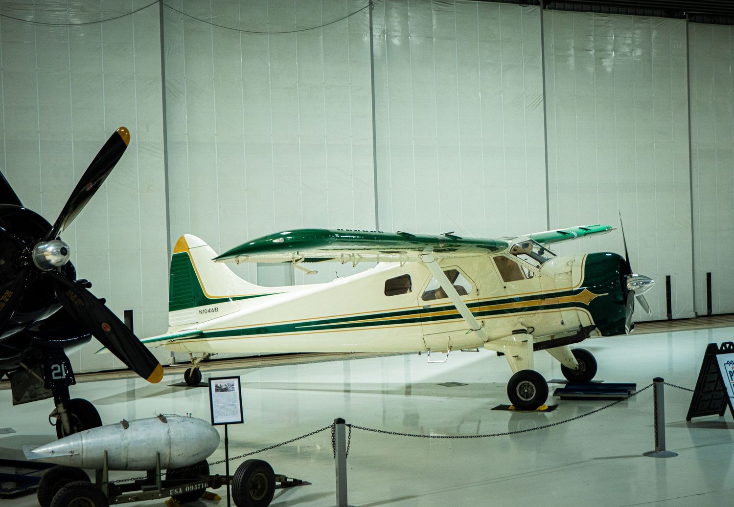 Vintage cream and green de Havilland Beaver bush plane on display in aviation museum hangar.