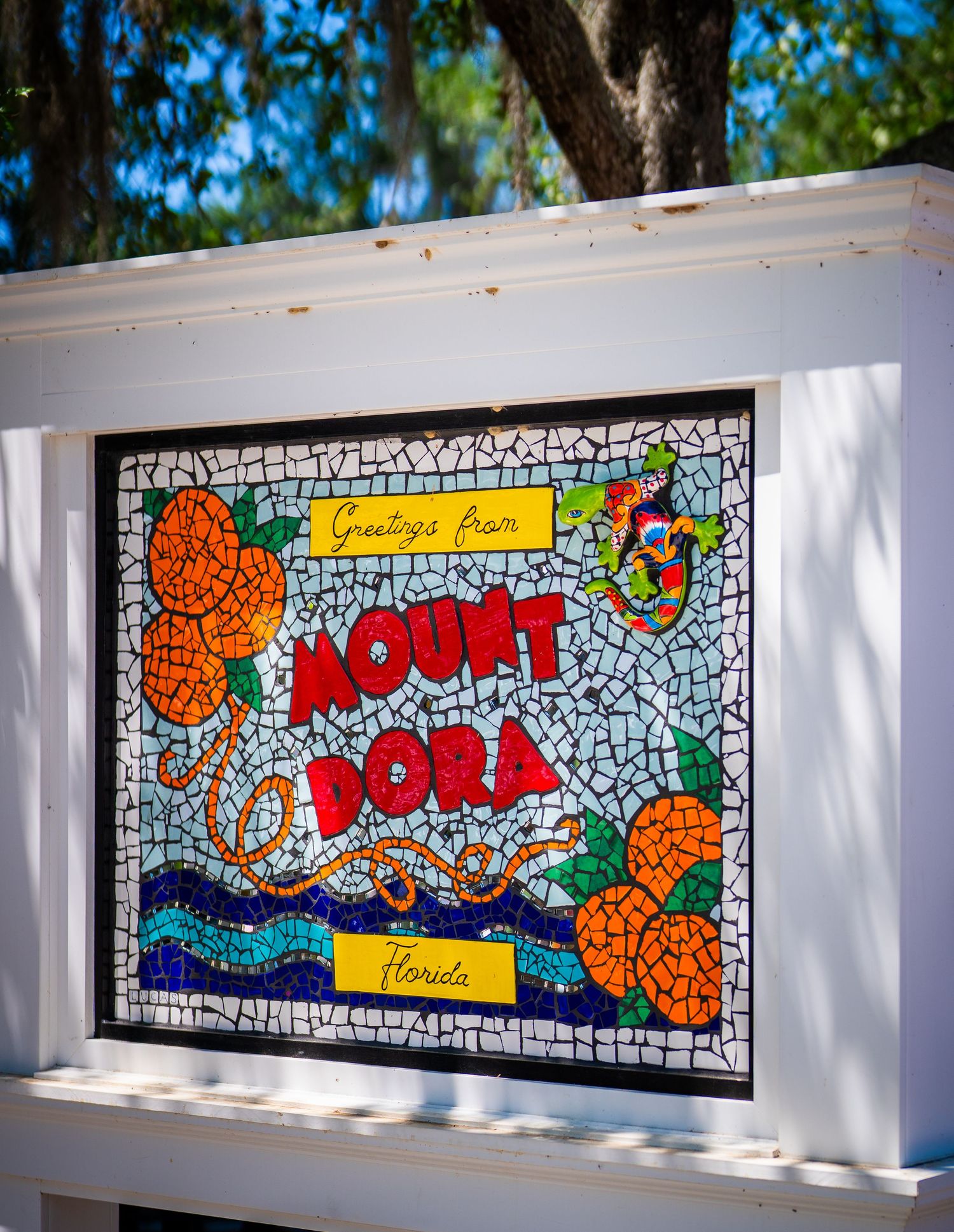 Colorful mosaic wall art with orange and blue tiles spelling out text.