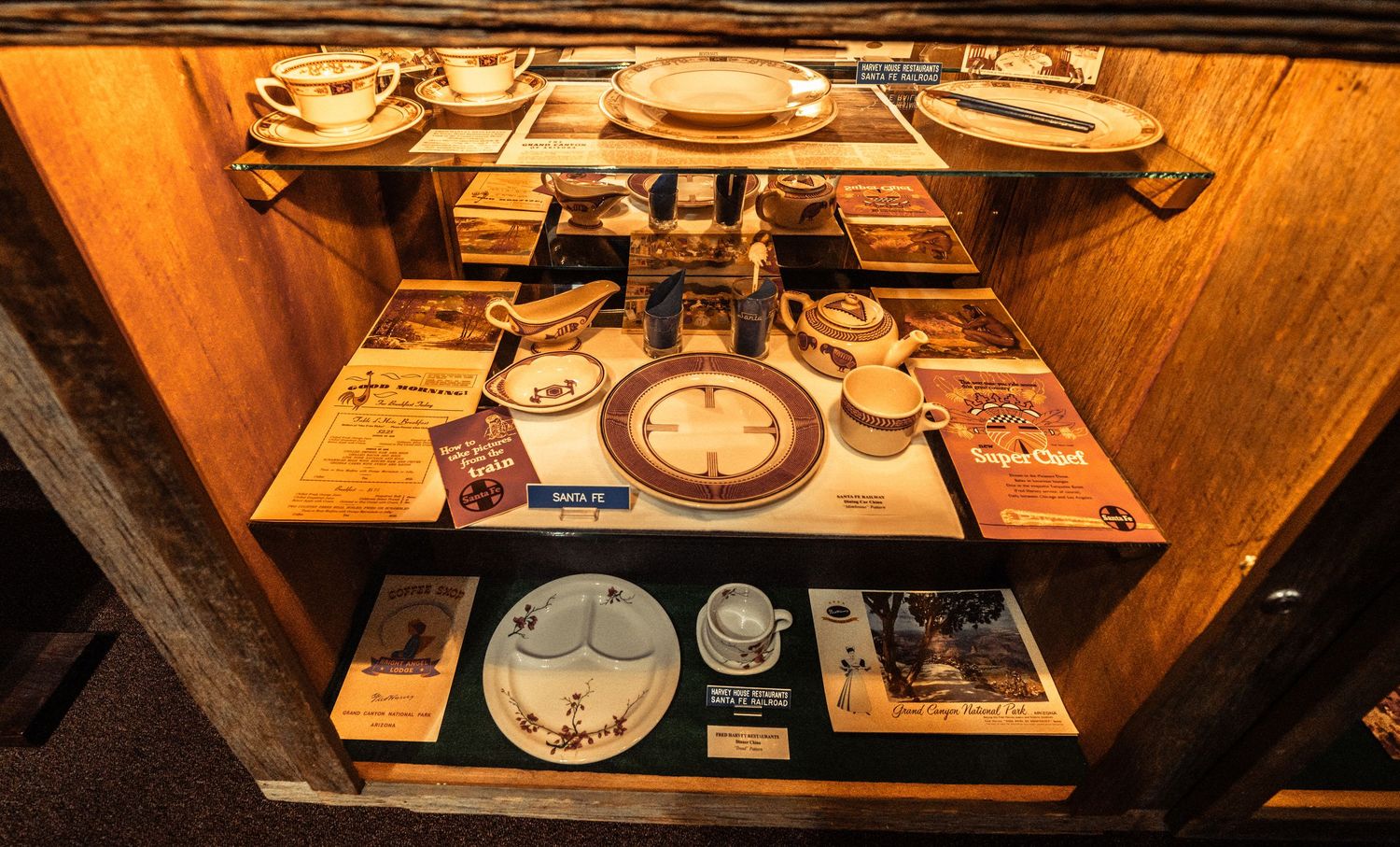 Glass display cases filled with antique railroad artifacts and memorabilia in warm wooden setting.