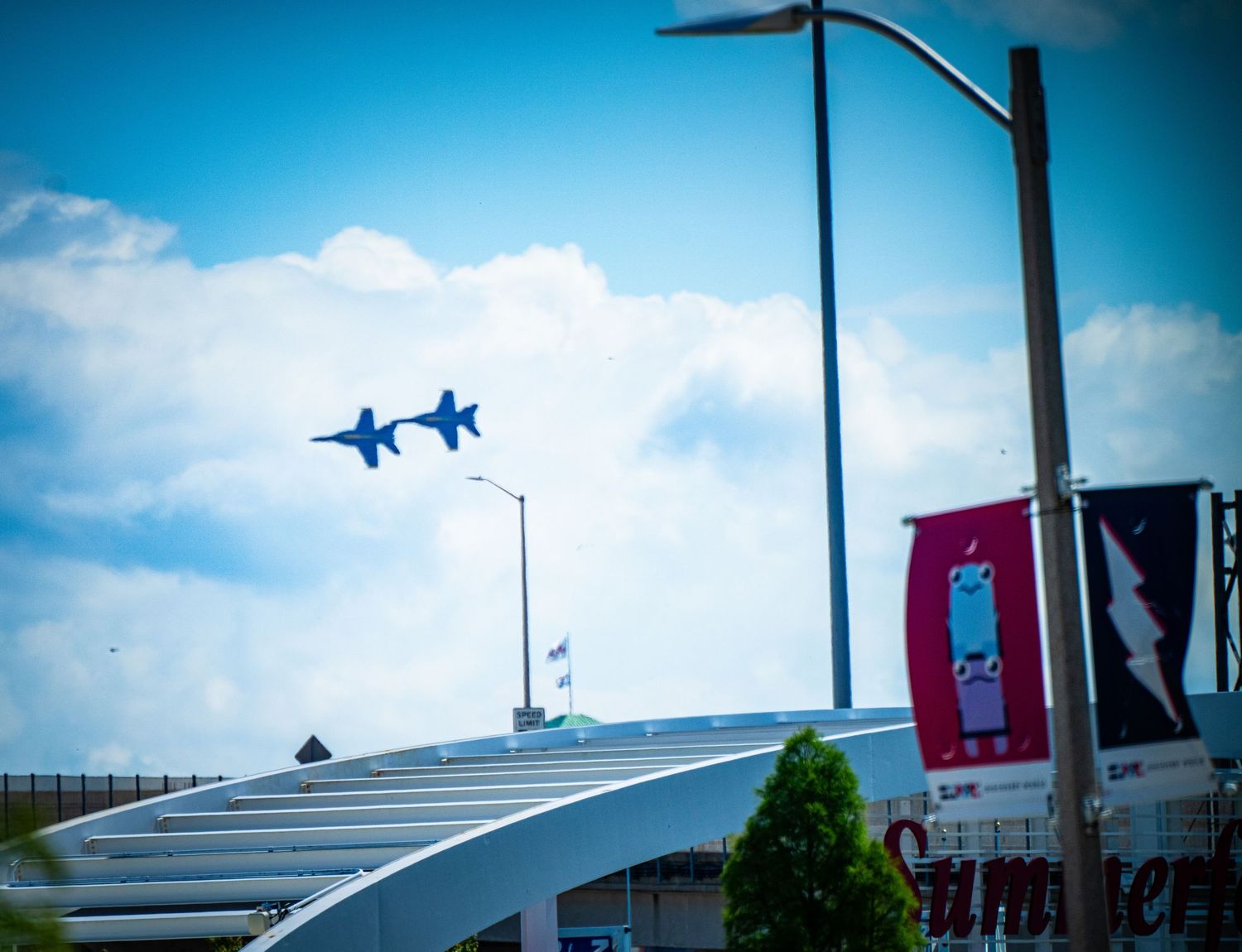Military jets flying over an urban area with buildings and street lights visible below.