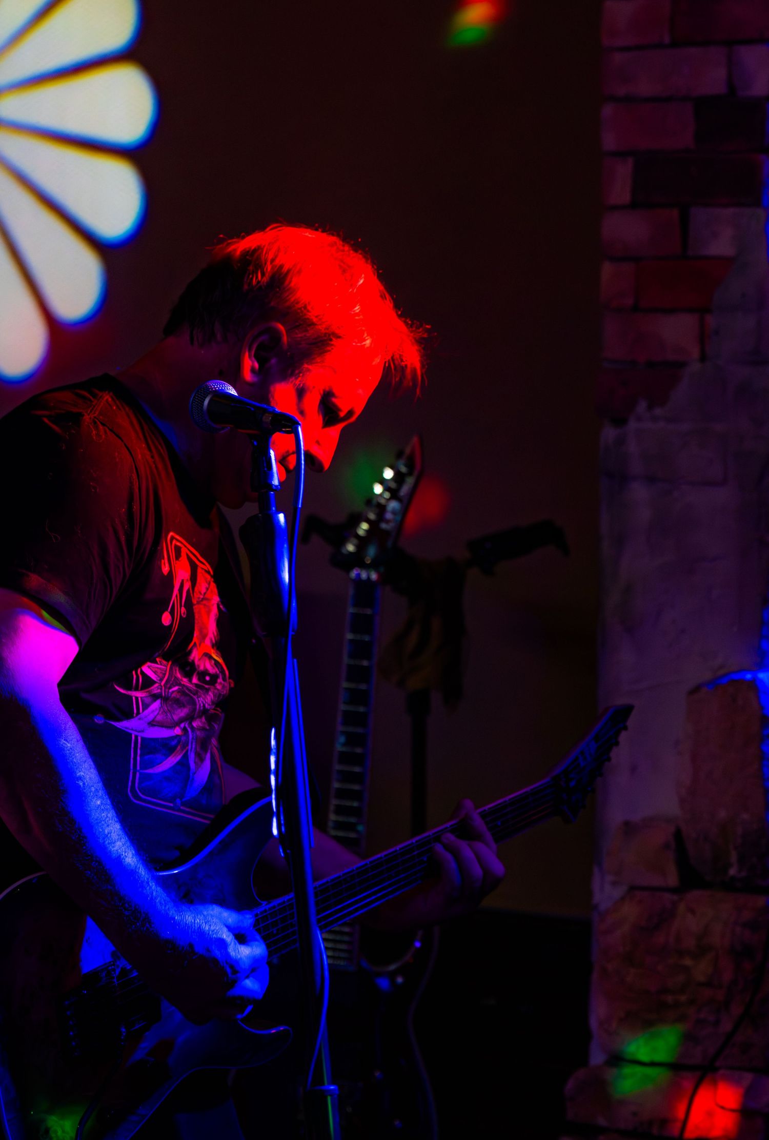 Musician performing under dramatic red and blue stage lighting during a live concert.