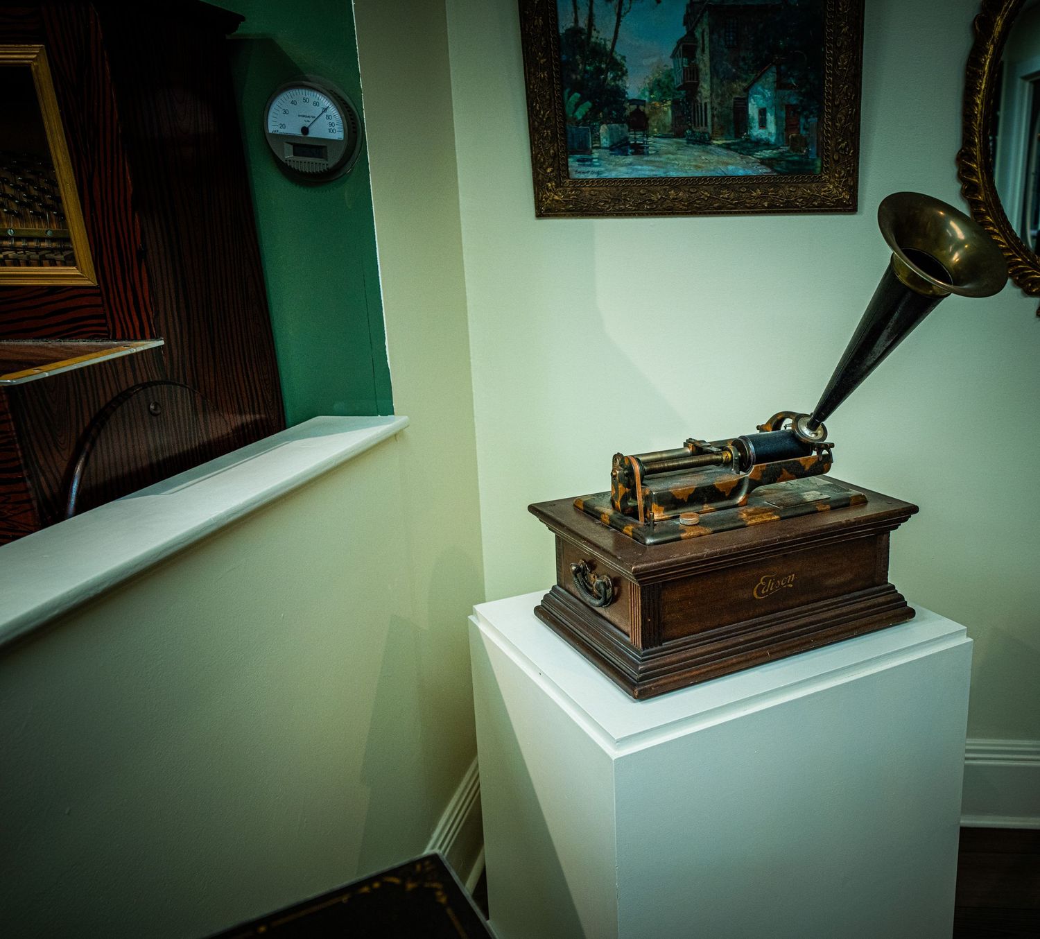 Vintage phonograph display in museum setting with green walls and ambient lighting.
