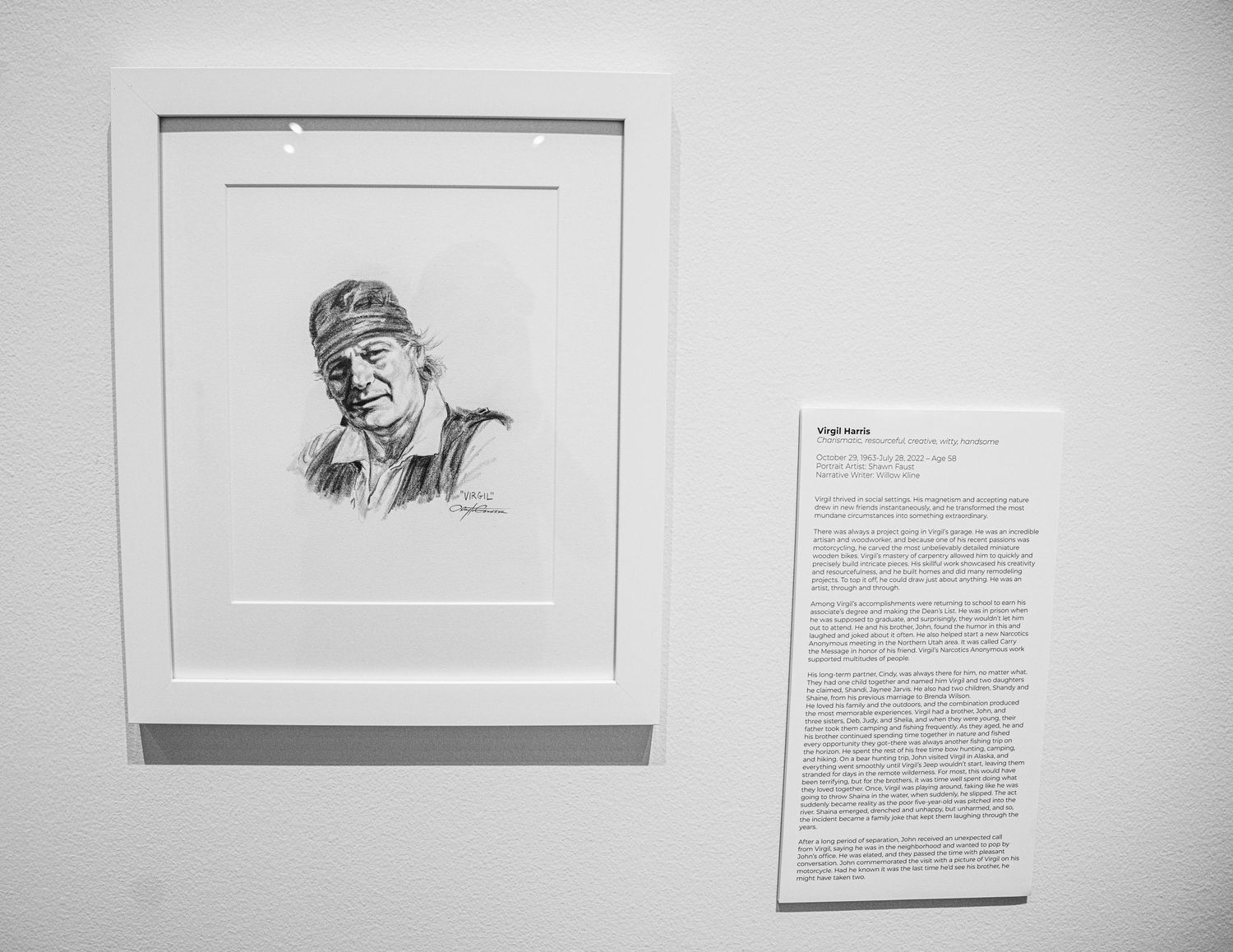 White gallery wall displaying a collection of portrait drawings and text installations.