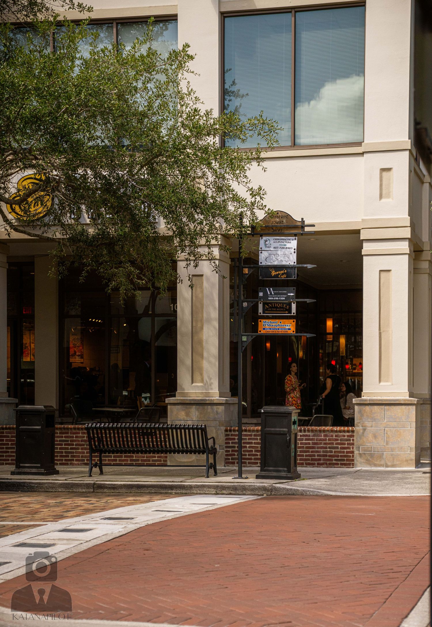 Commercial storefront with brick and stone columns along a covered walkway.
