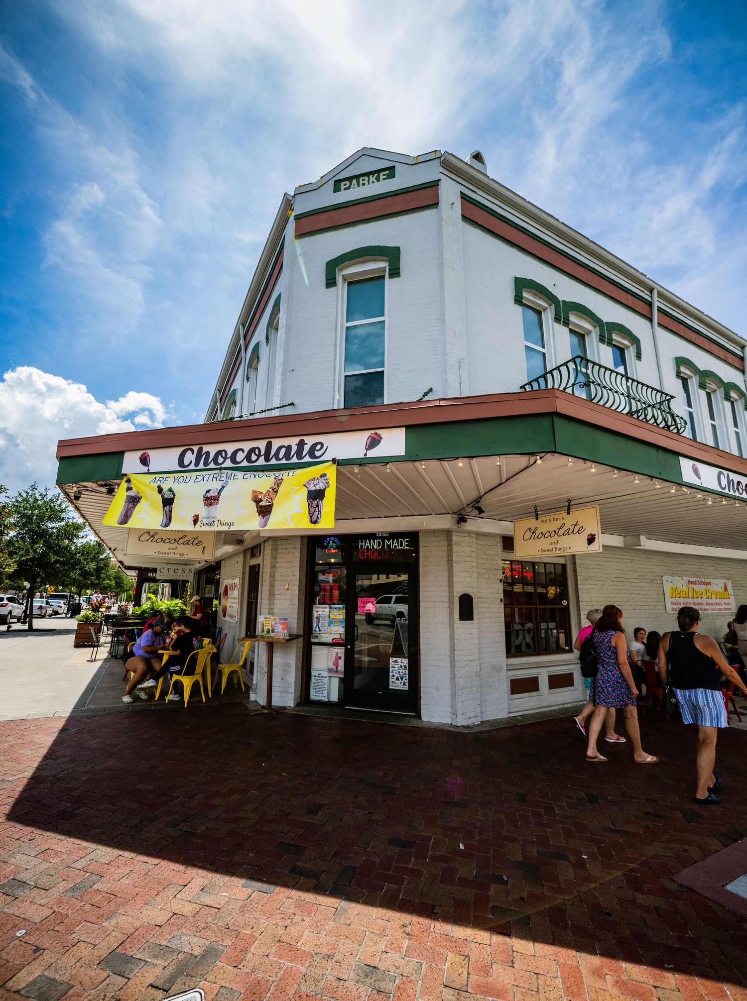 Shopping plaza with covered walkway and retail stores including a chocolate shop.