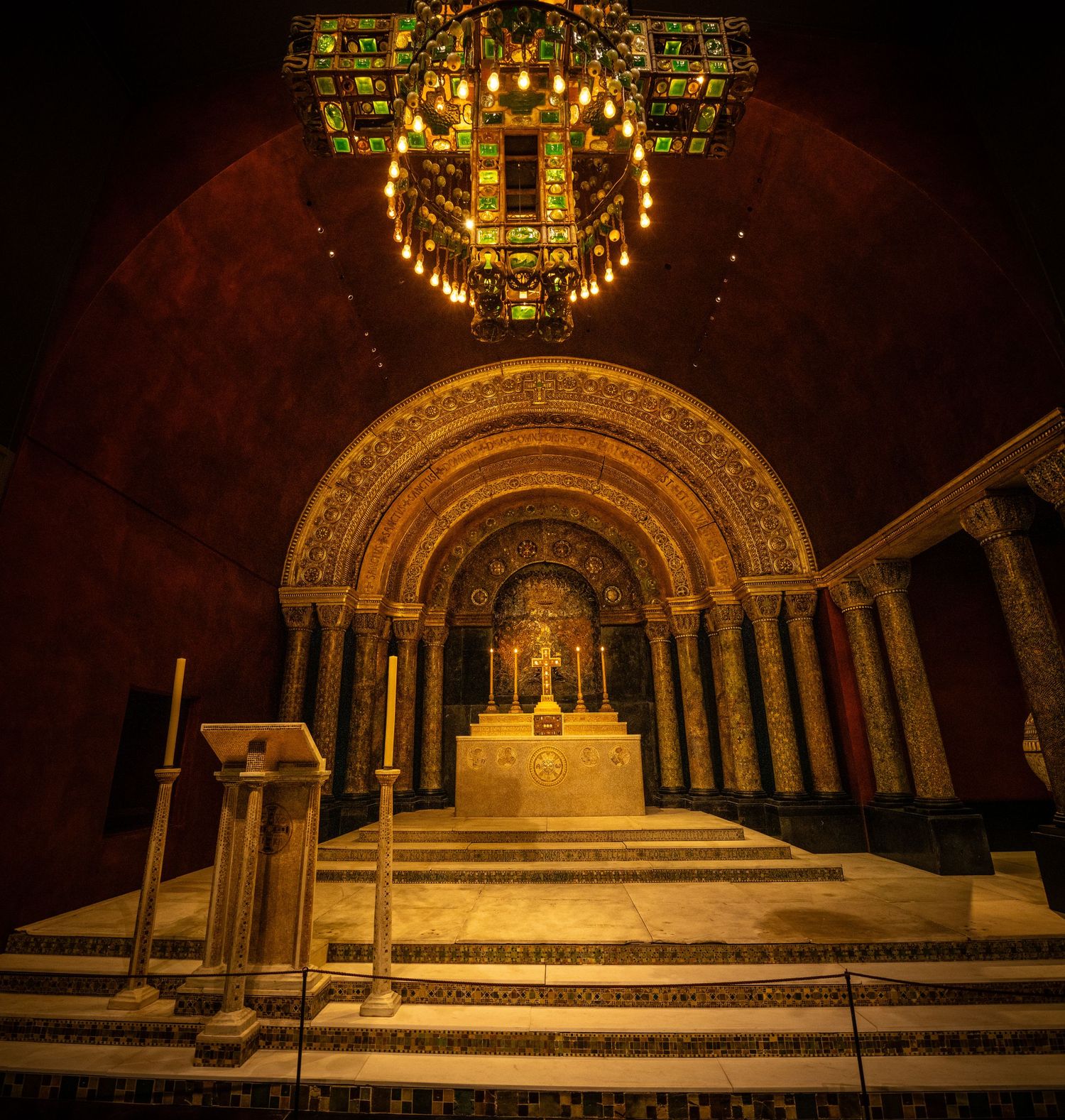 Grand illuminated altar area with arched architecture and stepped platform in warm golden lighting.