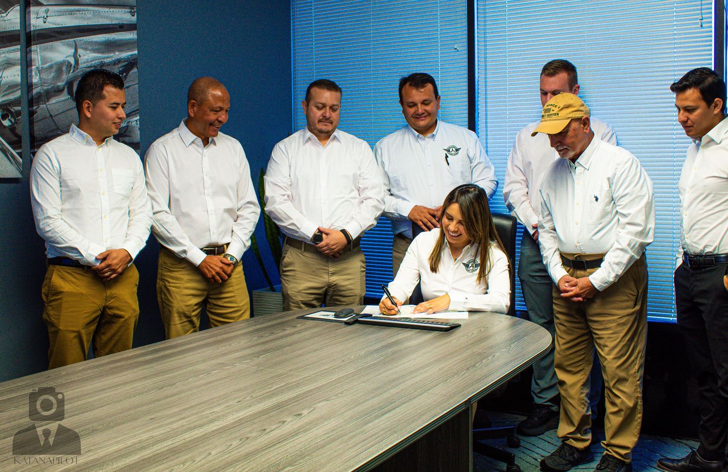 Group of aviation professionals seated at long conference table in meeting room.