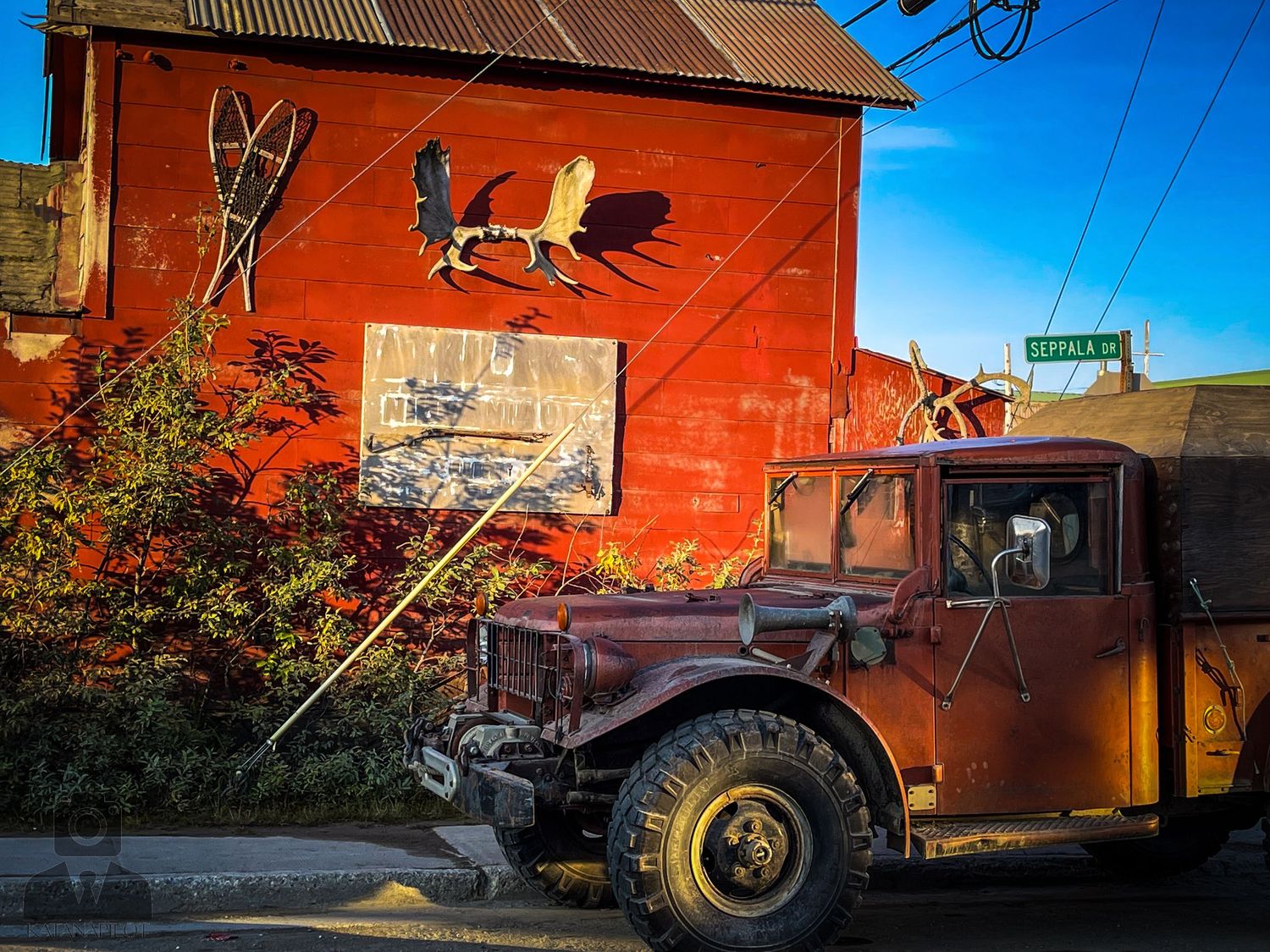 Rustic red buildings and equipment against a bright blue sky in an industrial setting.