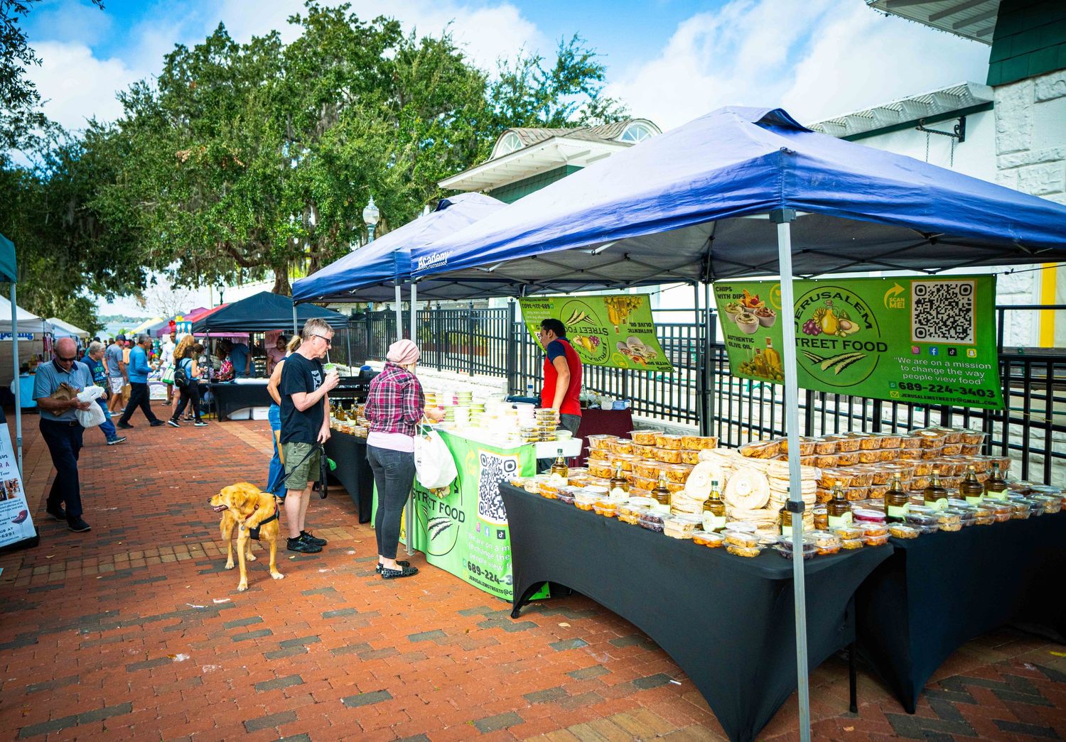 Vendors set up tents and tables at an outdoor farmers market on a sunny day.