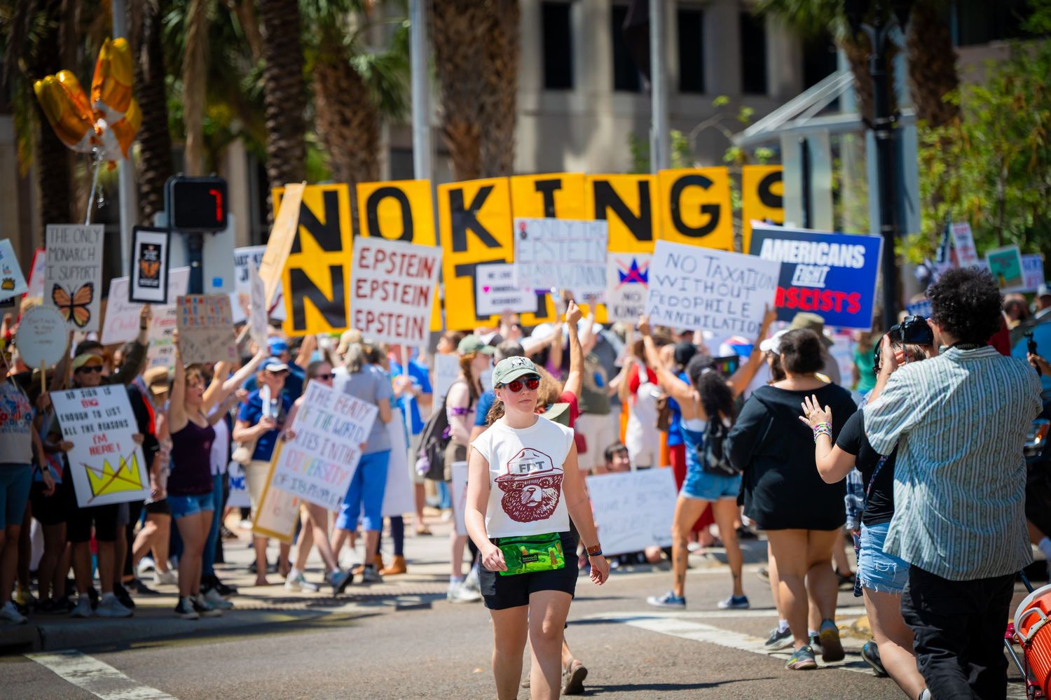 Protesters hold signs at a street demonstration with a prominent 'NO KING' message visible in yellow letters.