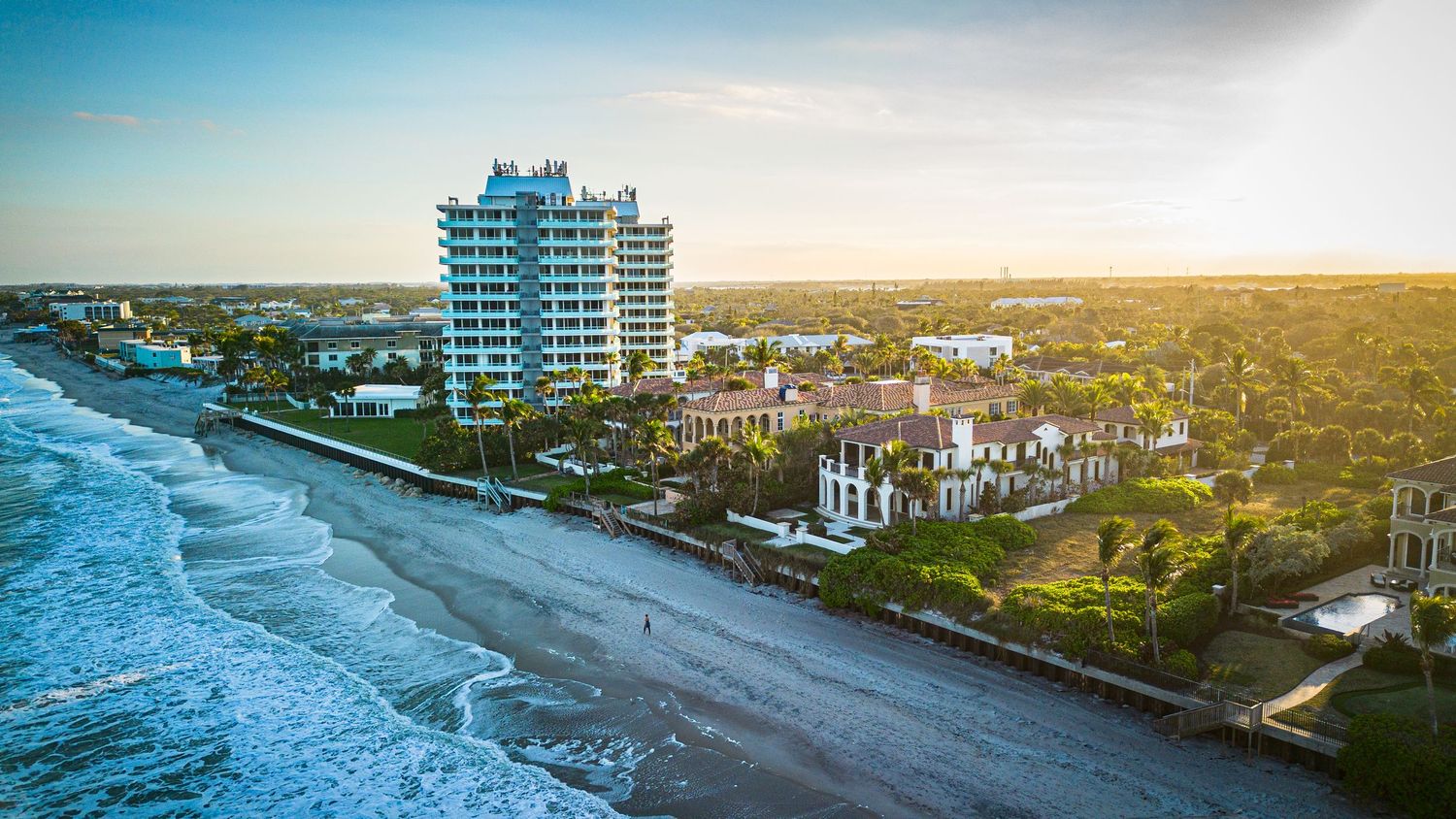 Beachfront high-rise condominium tower overlooking the Atlantic Ocean at sunset.
