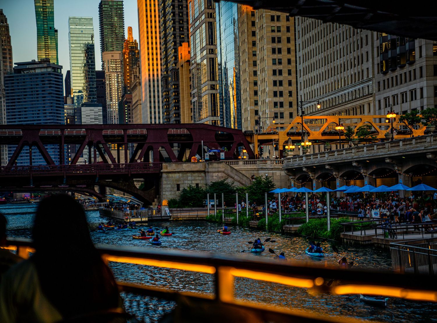 Downtown Chicago cityscape at dusk with illuminated buildings reflecting on the river.