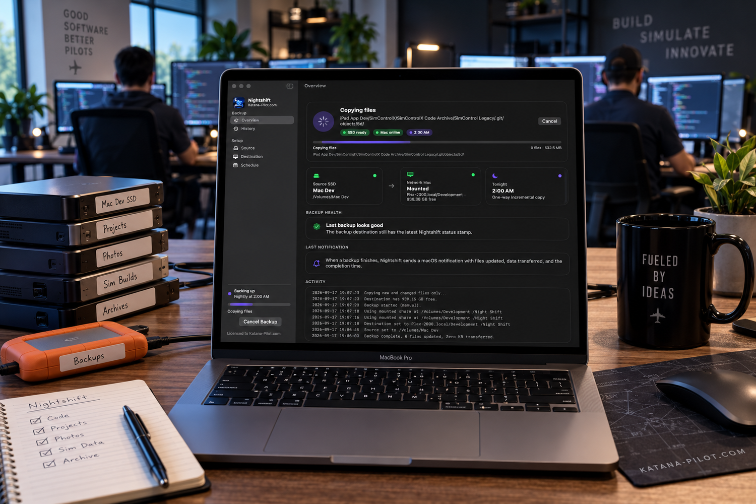 A developer works on a dark-themed coding interface on a MacBook Pro in a modern tech office workspace.