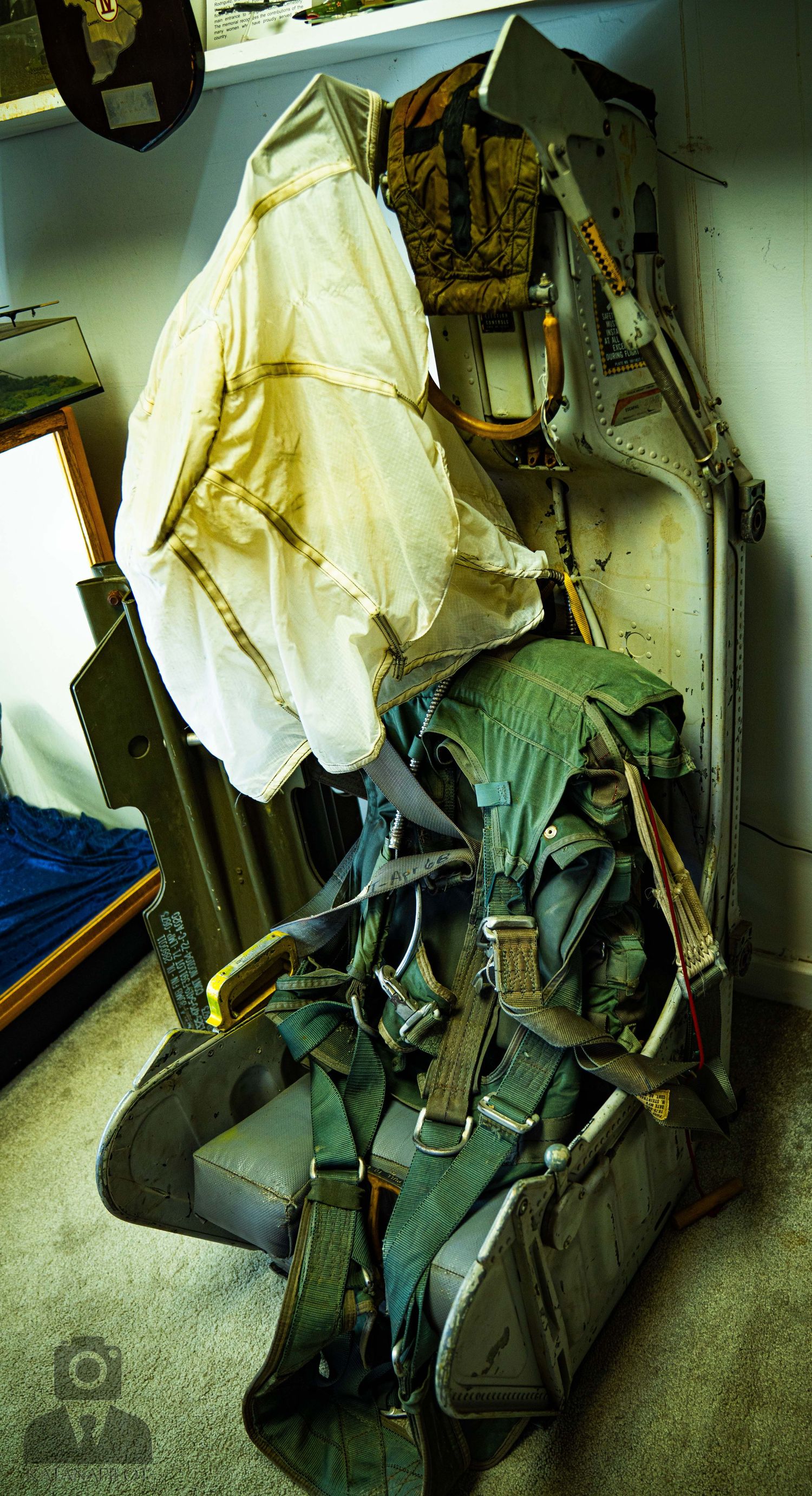 Military flight suits and aviation gear hanging on storage hooks.