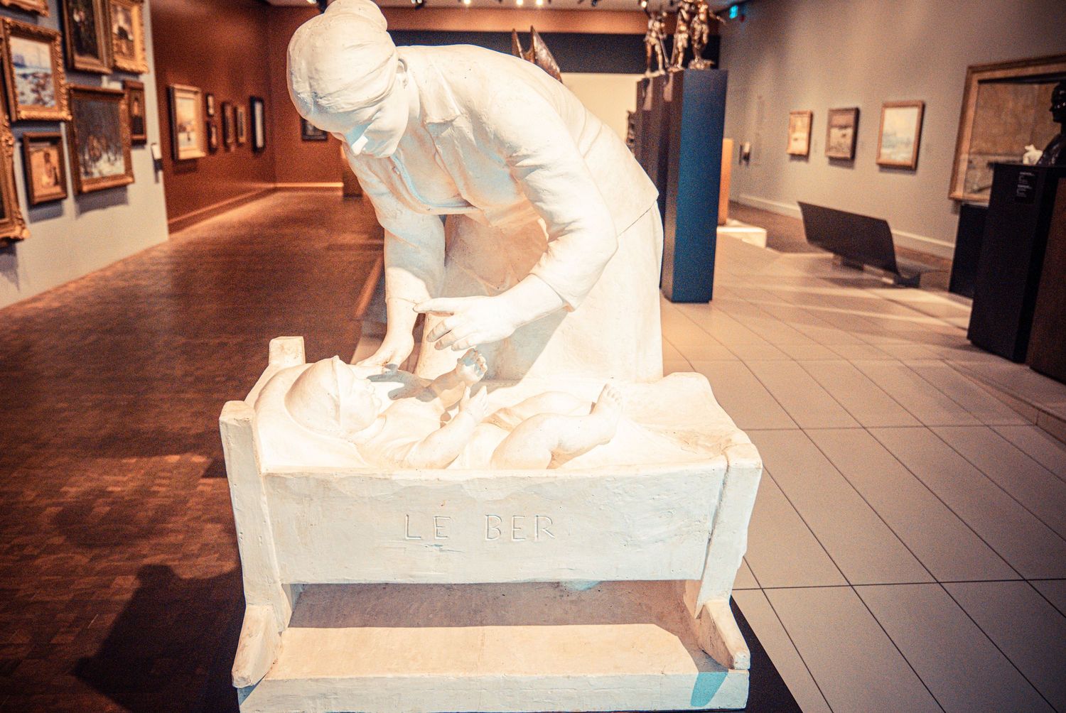 White marble sculptures displayed in a museum gallery with dark flooring.