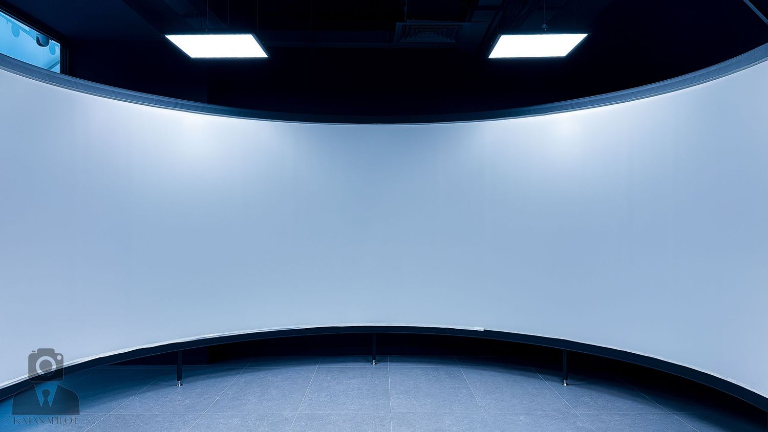 Modern flight simulator facility with curved white walls and black ceiling panels.