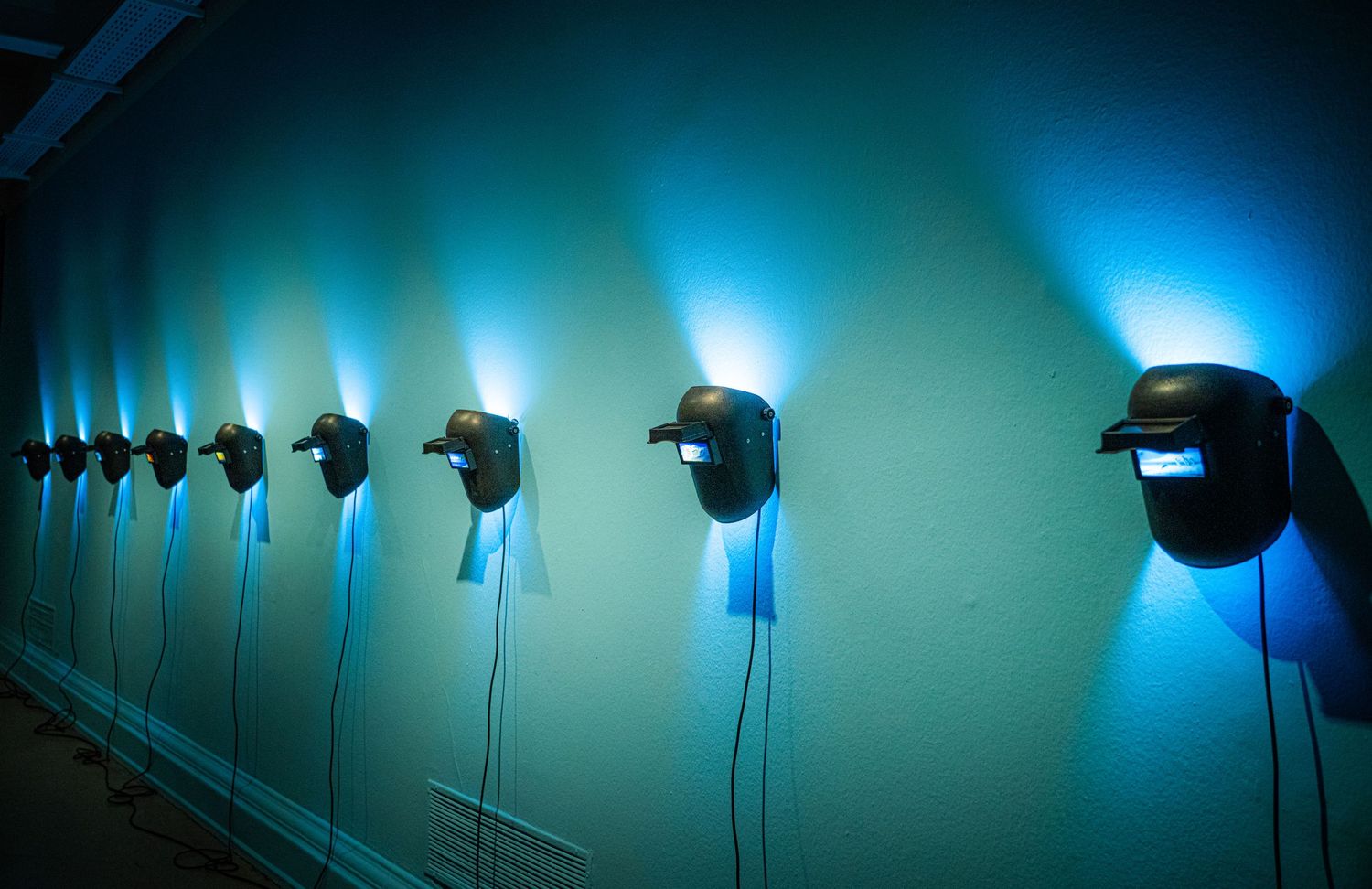 Row of blue illuminated wall lights creating an ethereal glow against a dark background.