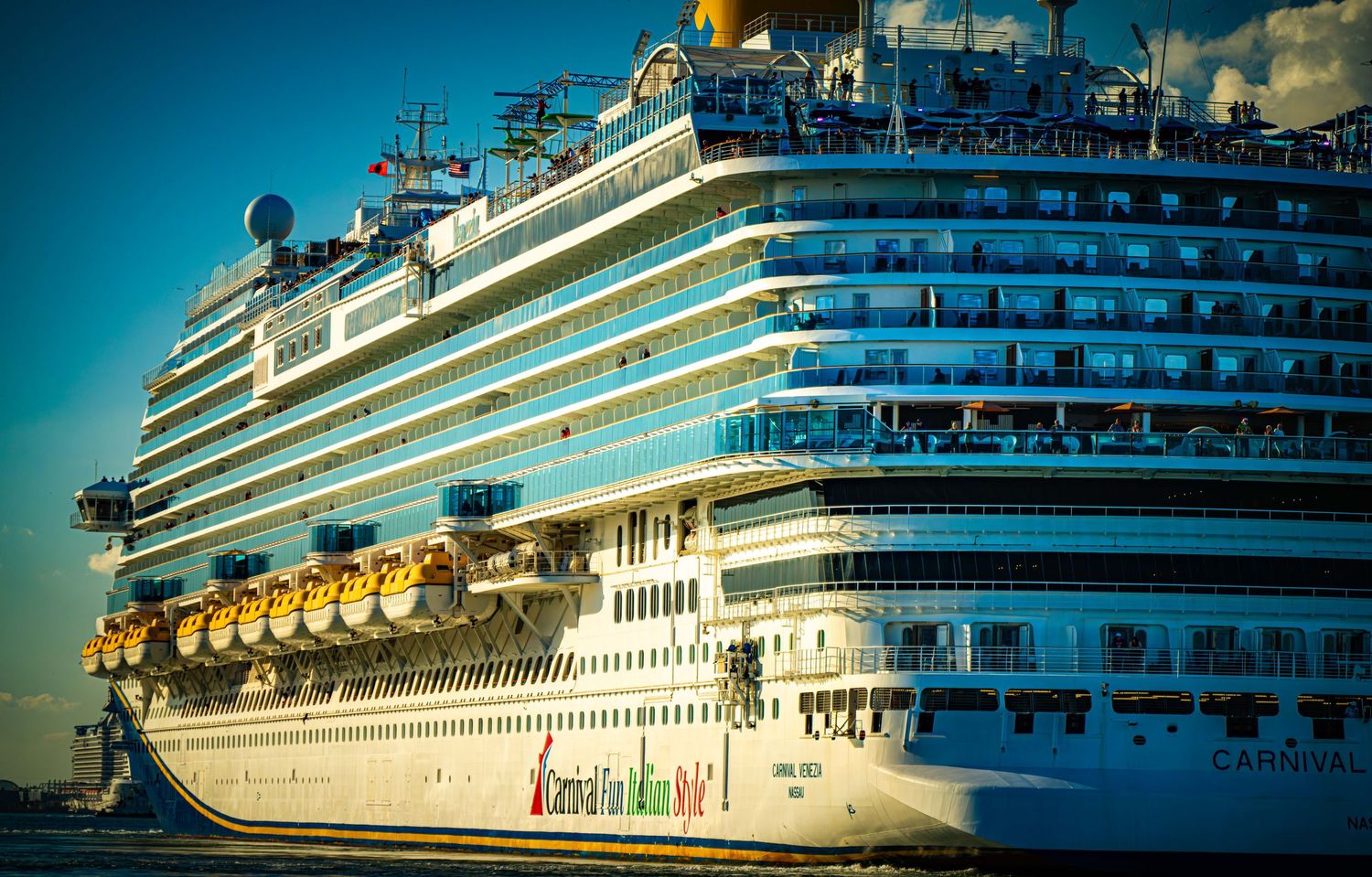Several large white cruise ships lined up at port against a vibrant blue sky and ocean backdrop.
