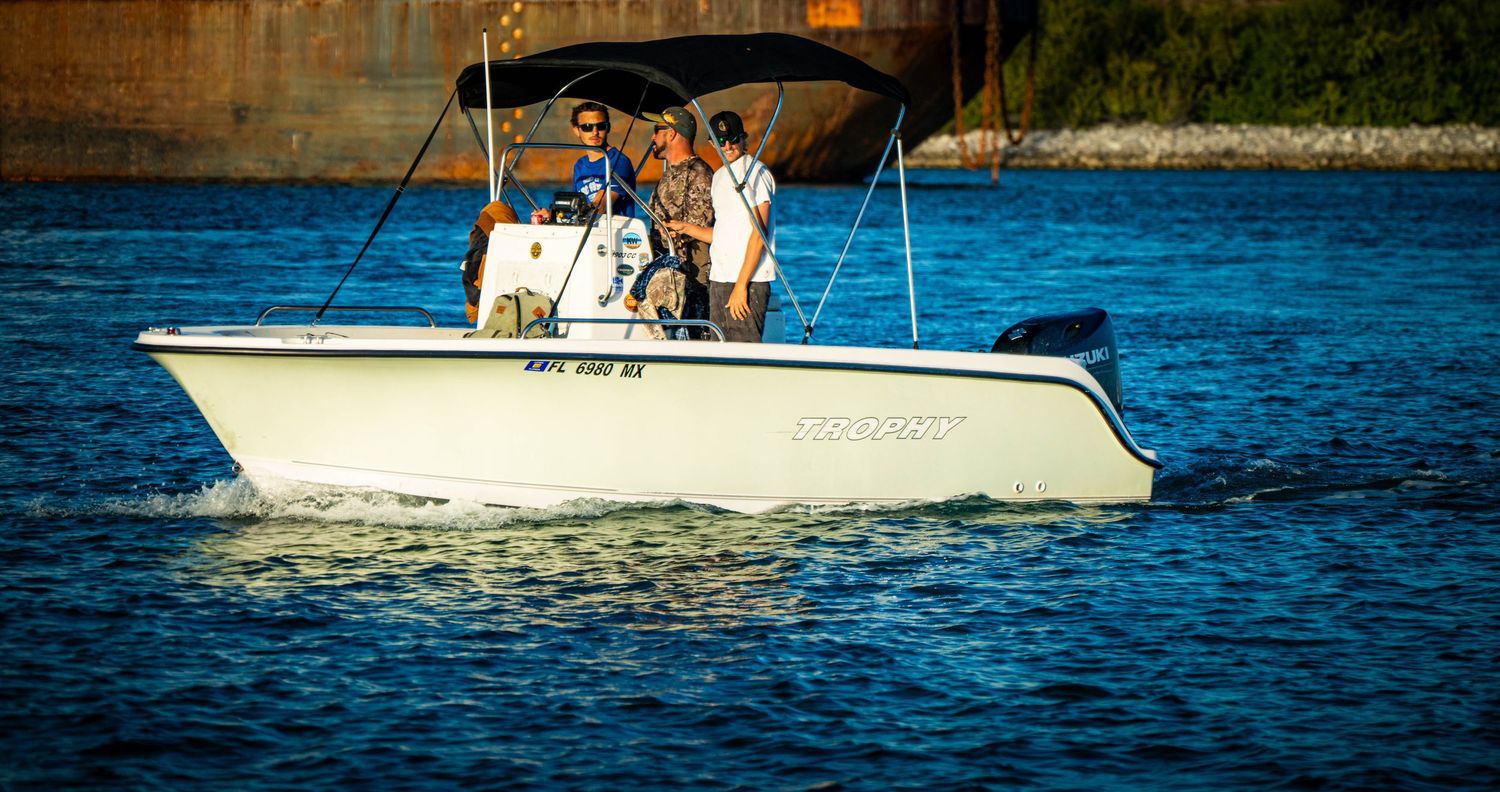 Several boats cruise along bright blue waters on a sunny day near a shoreline.