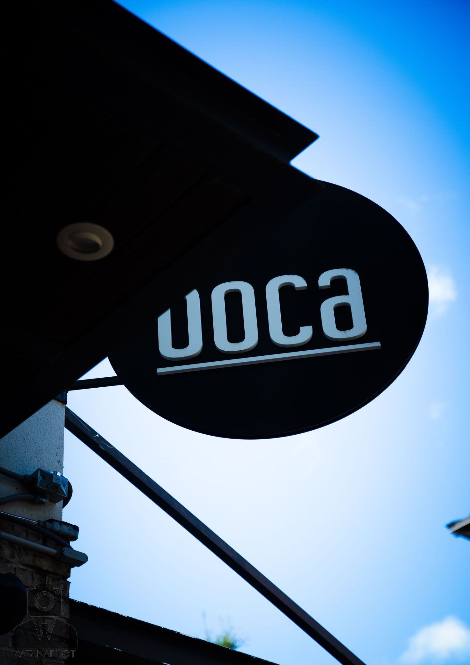 Silhouetted signage against bright blue sky showing 'DOCO' text.