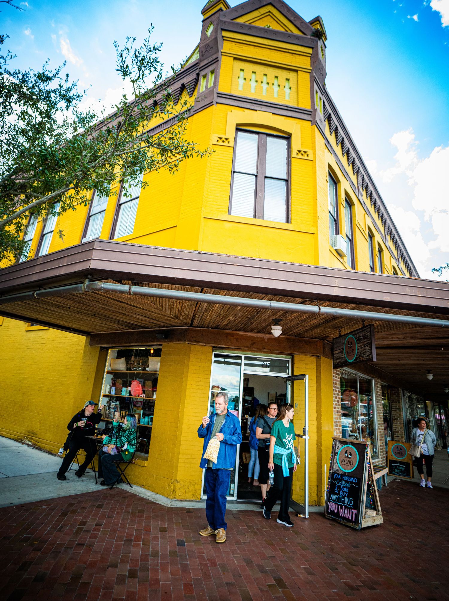 A series of exterior views showing a bright yellow commercial building with awnings and storefronts under a blue sky.