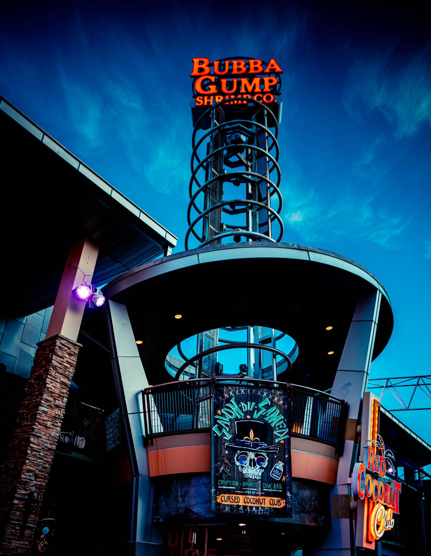 Bubba Gump Shrimp Co. restaurant exterior signage and entrance illuminated at night against a dark blue sky.