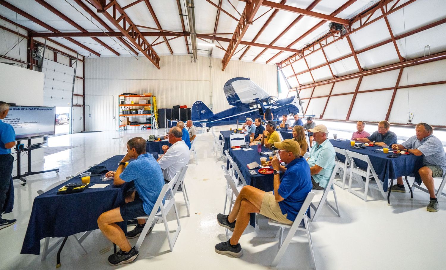 Long view of a training room with exposed ceiling beams and rows of white chairs.
