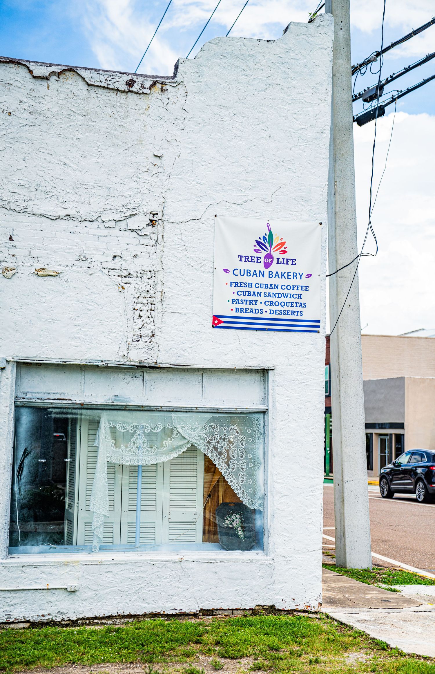 White painted brick building with a vintage window display and utility pole.