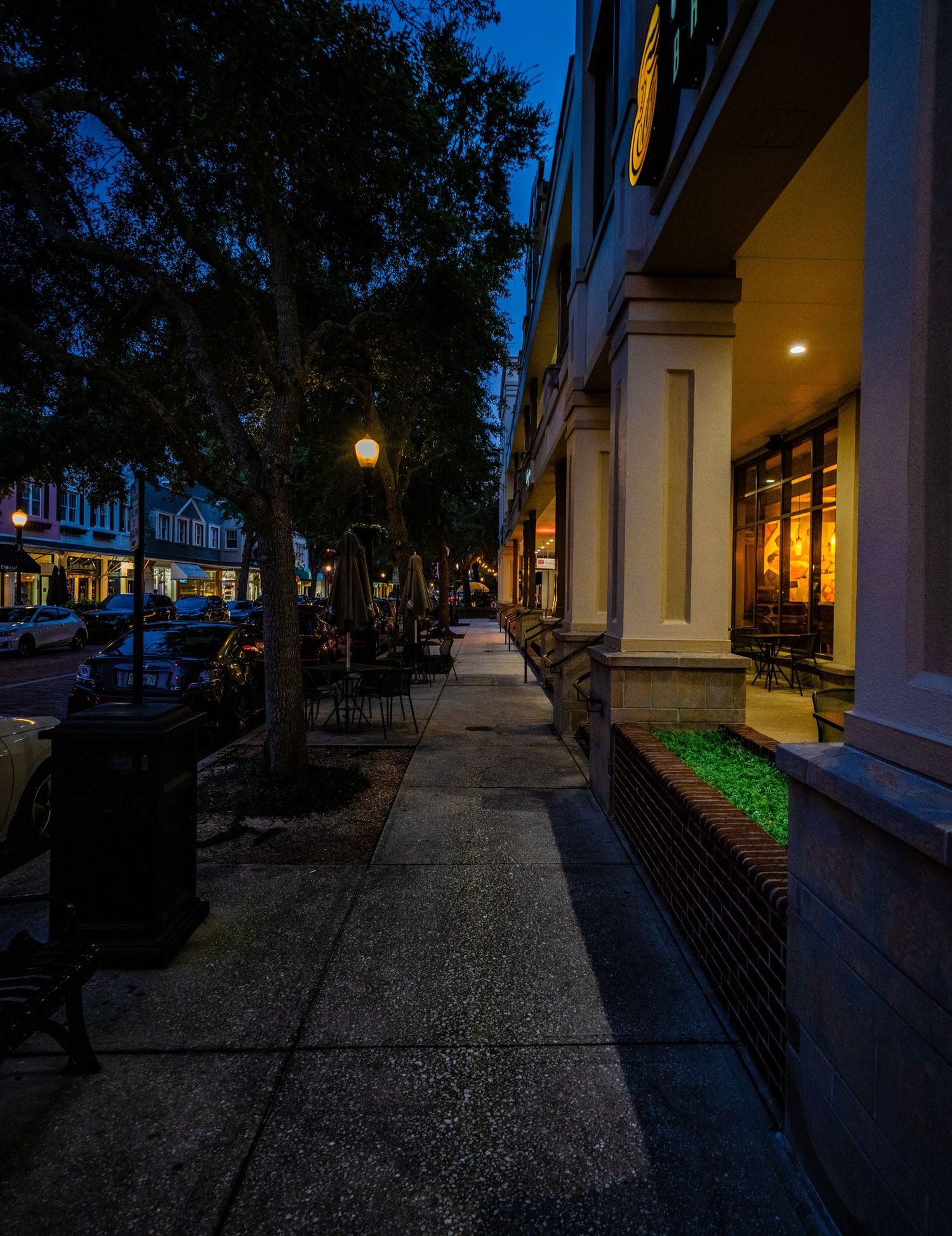 Walkway between buildings with ambient lighting and architectural columns creating dramatic shadows.