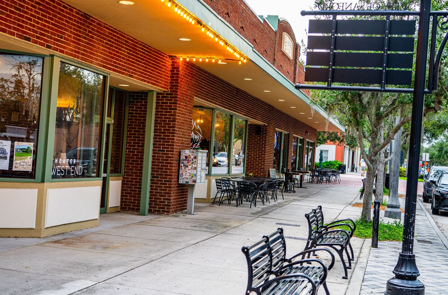 Brick sidewalk with decorative black metal benches under a covered shopping arcade.