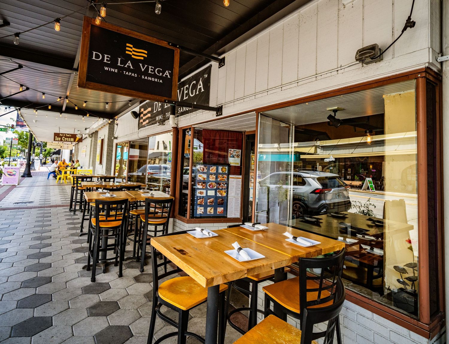 Interior of a casual dining restaurant with wooden tables and industrial-style lighting.