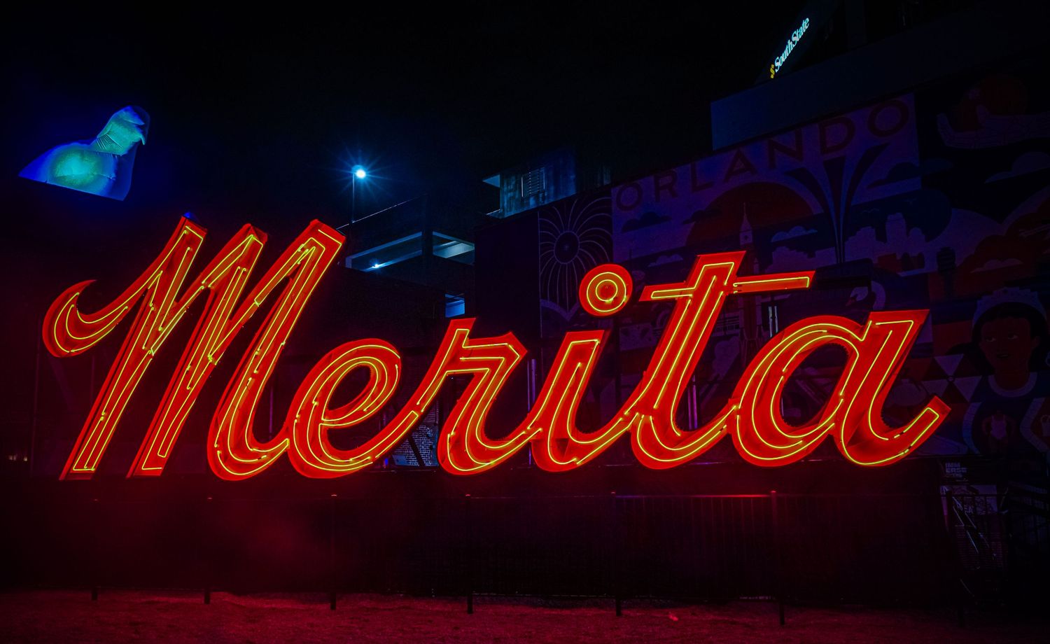 Colorful neon signs illuminate a dark urban street with glowing blue and red text.