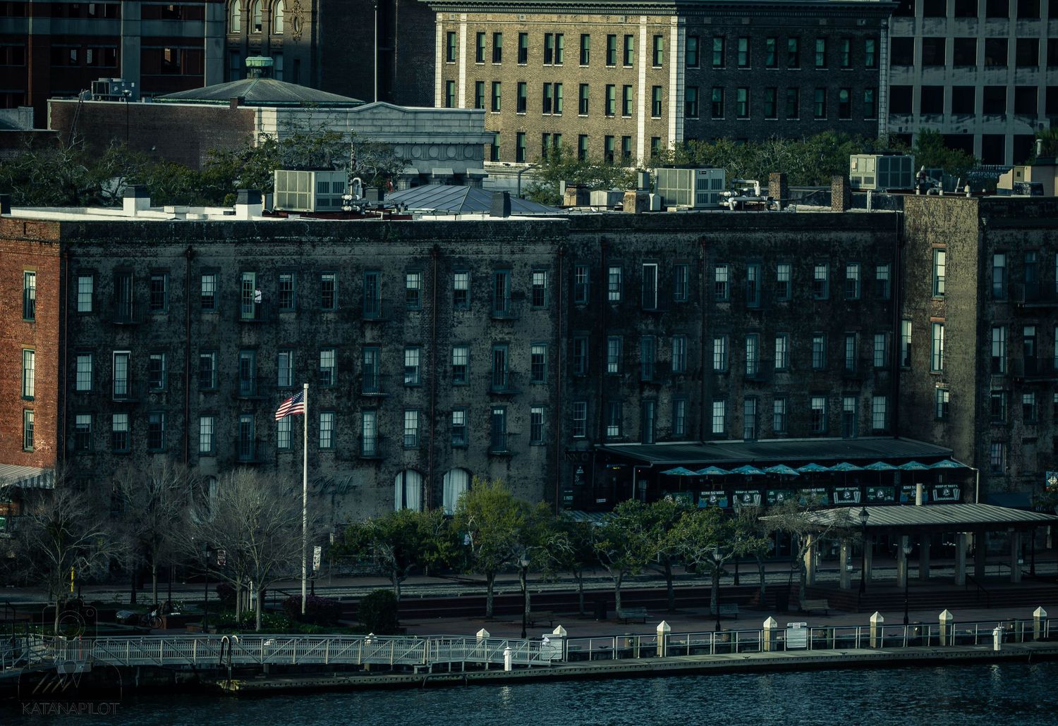 Panoramic view of historic brick buildings along a waterfront with boats docked at the harbor during dusk.