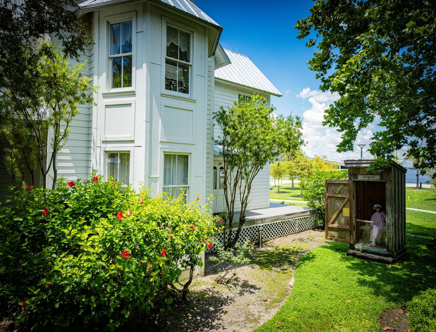 White historic building exterior with green lawn and trees on a sunny day.