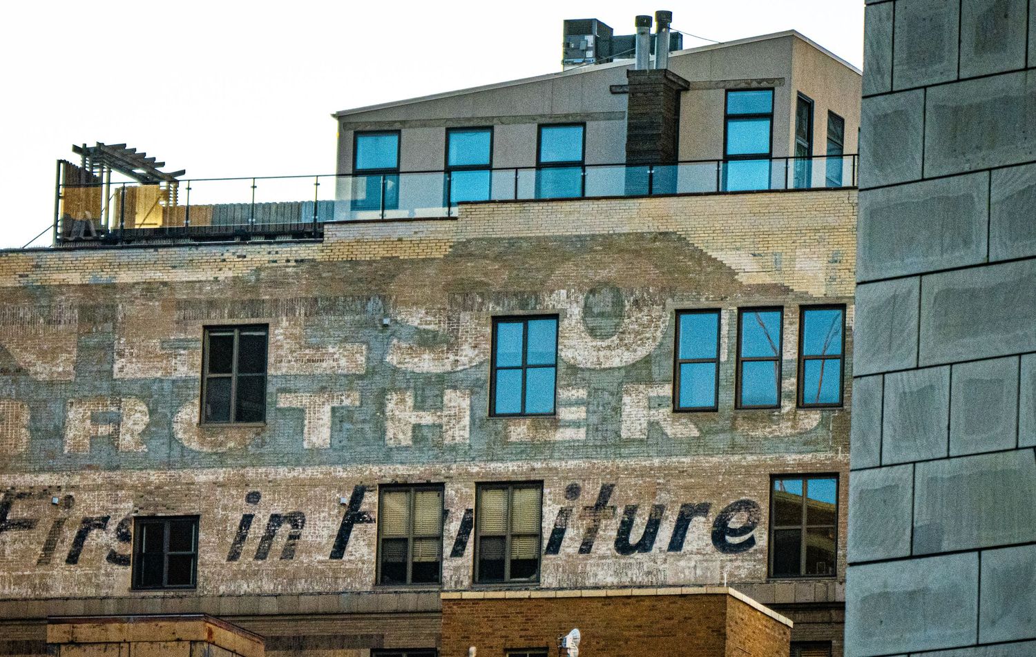 Modern urban building exterior with faded vintage signage and text.