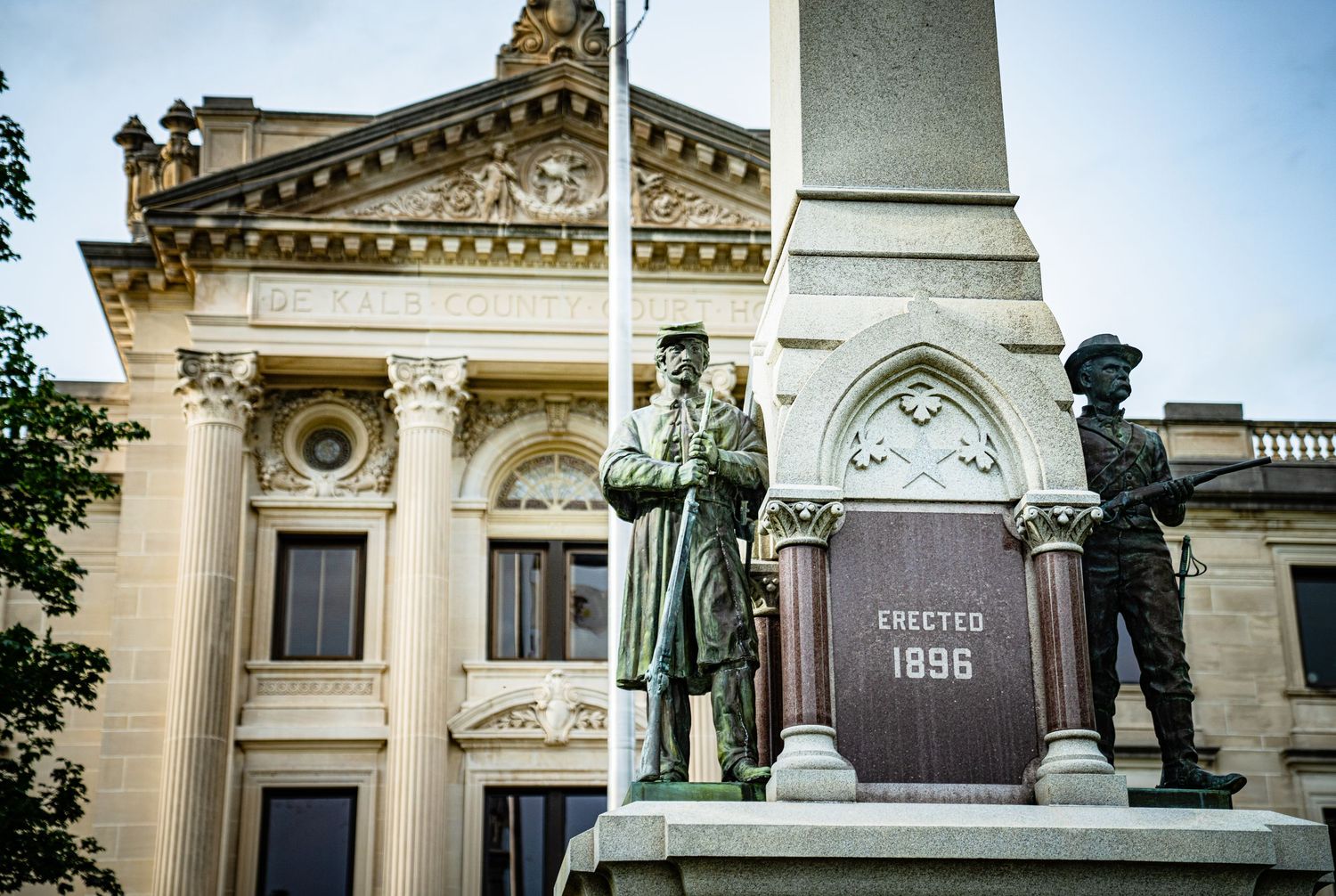Historic limestone courthouse with decorative architectural details and monuments photographed in sections.