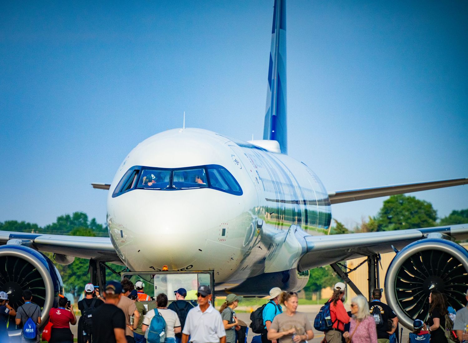 Commercial passenger aircraft on tarmac with crowd of people nearby.
