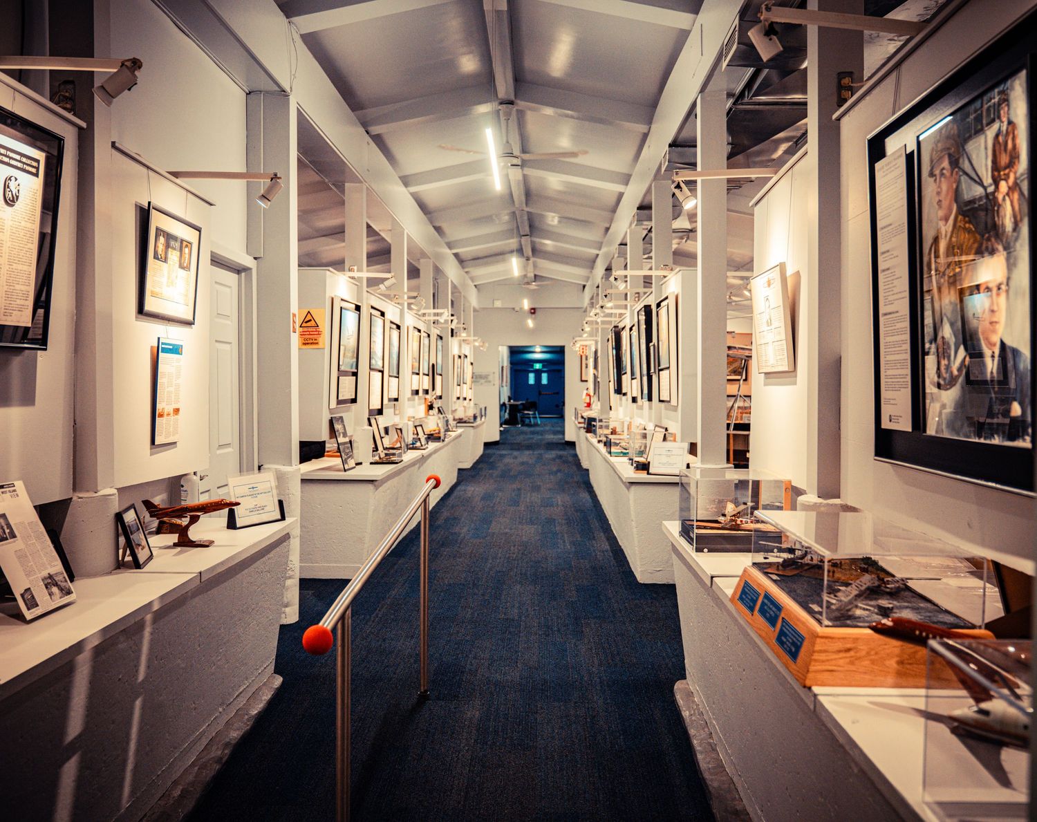 Long museum corridor with aviation exhibits and displays along white walls.