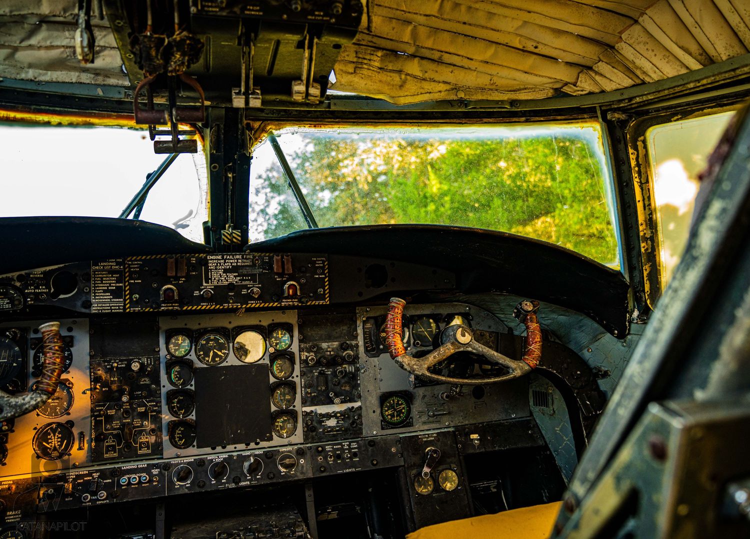 Weathered airplane cockpit instruments and control panels in golden sunlight.