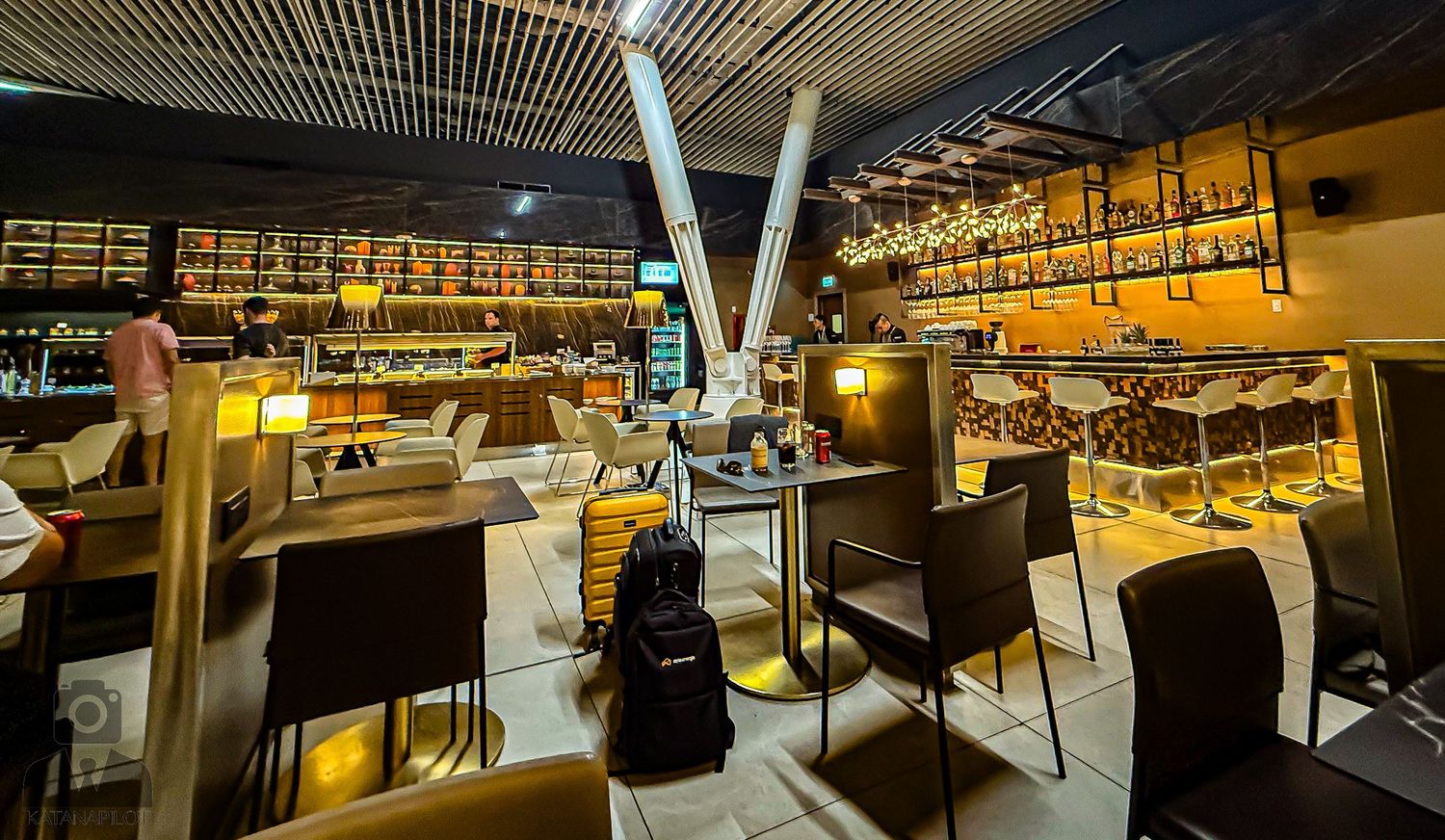 Modern lounge area with industrial ceiling design and warm lighting.