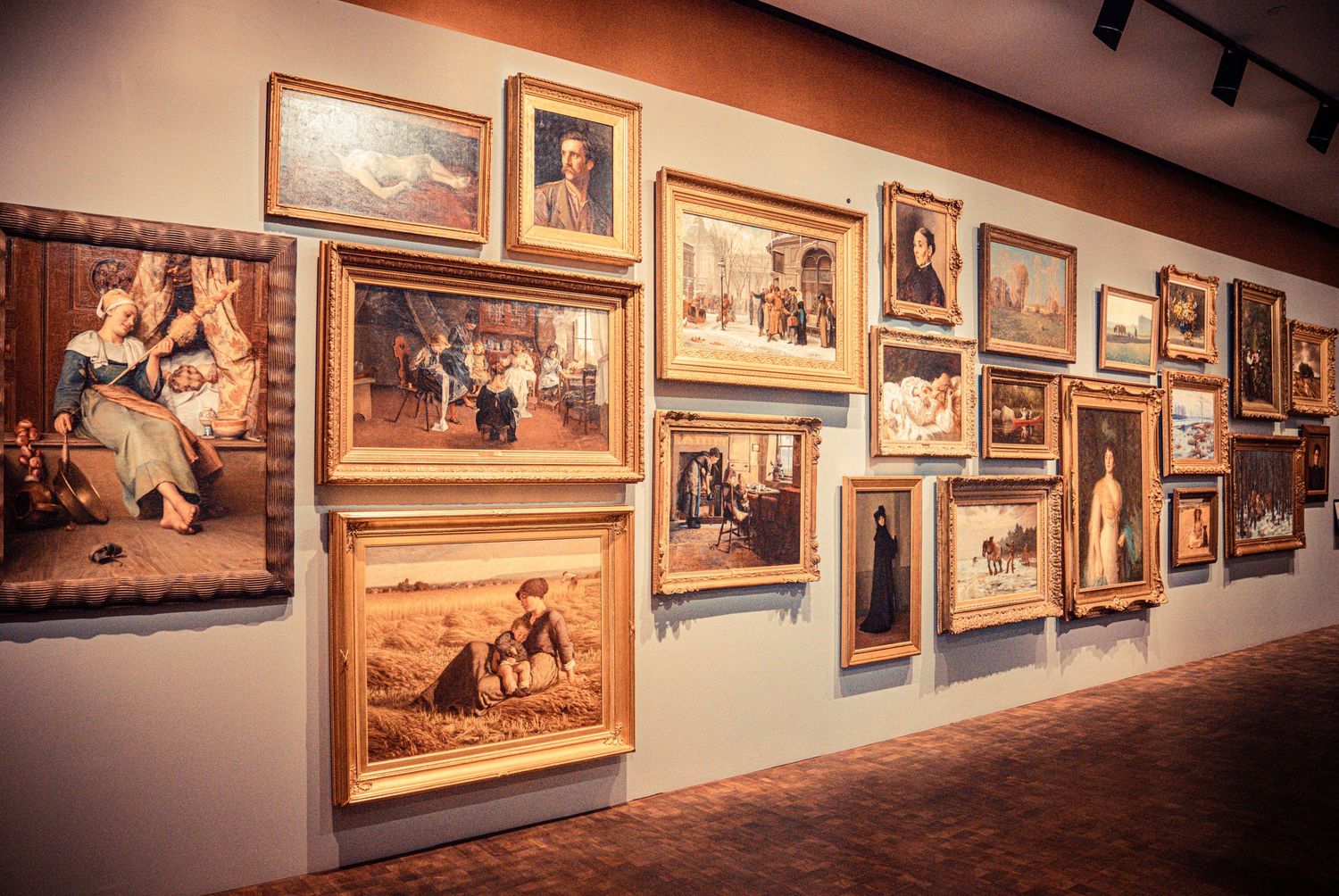 Gallery wall featuring a series of vintage paintings and photographs in ornate gold frames.