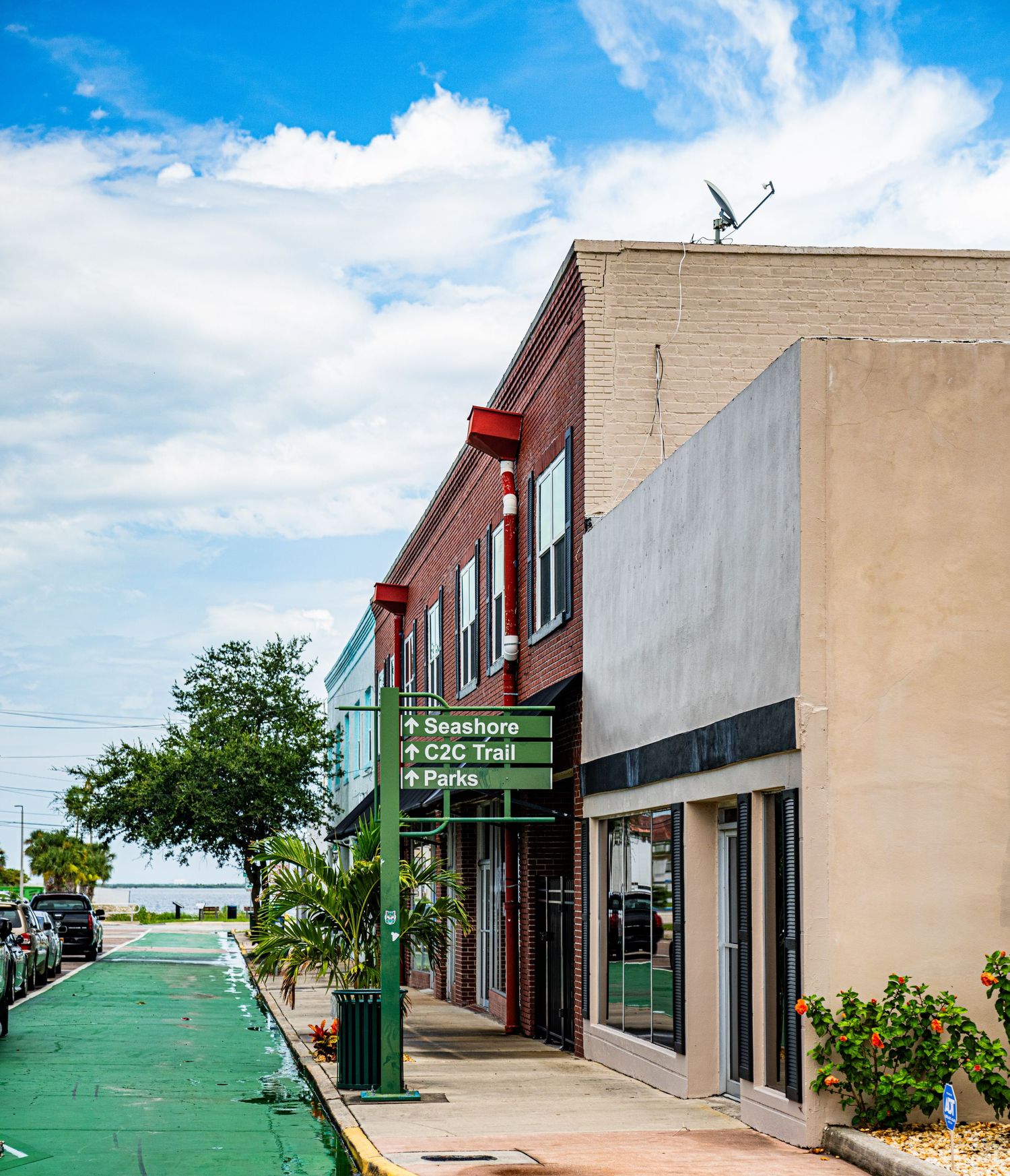 Commercial strip mall exterior with green lamp posts against blue sky.