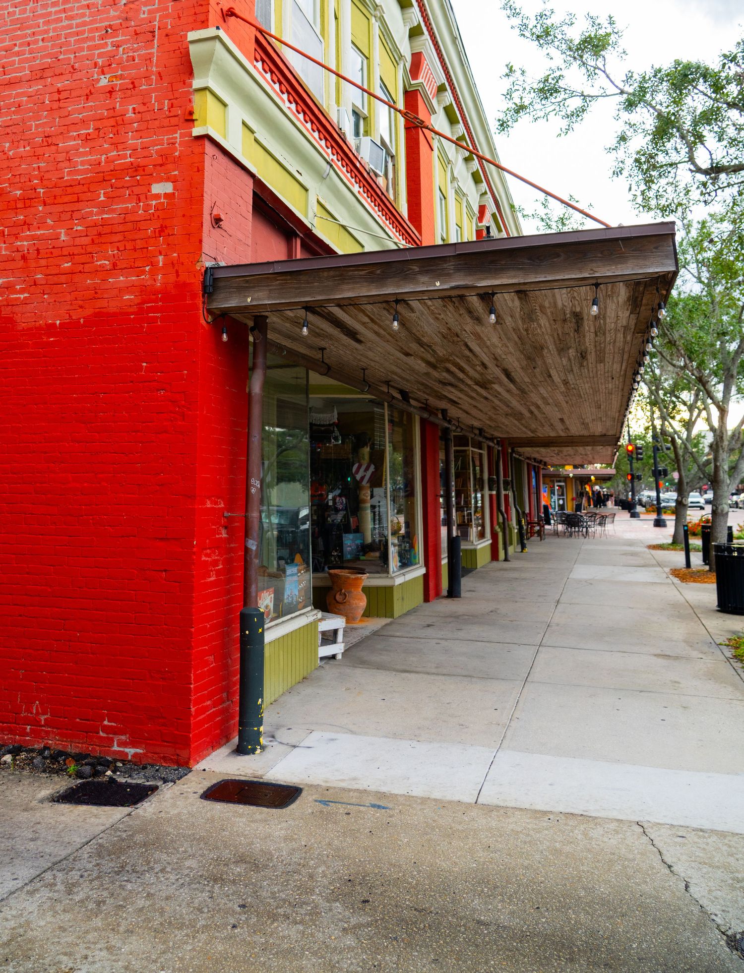 Historic brick storefronts with covered walkways and red walls line a downtown shopping district.