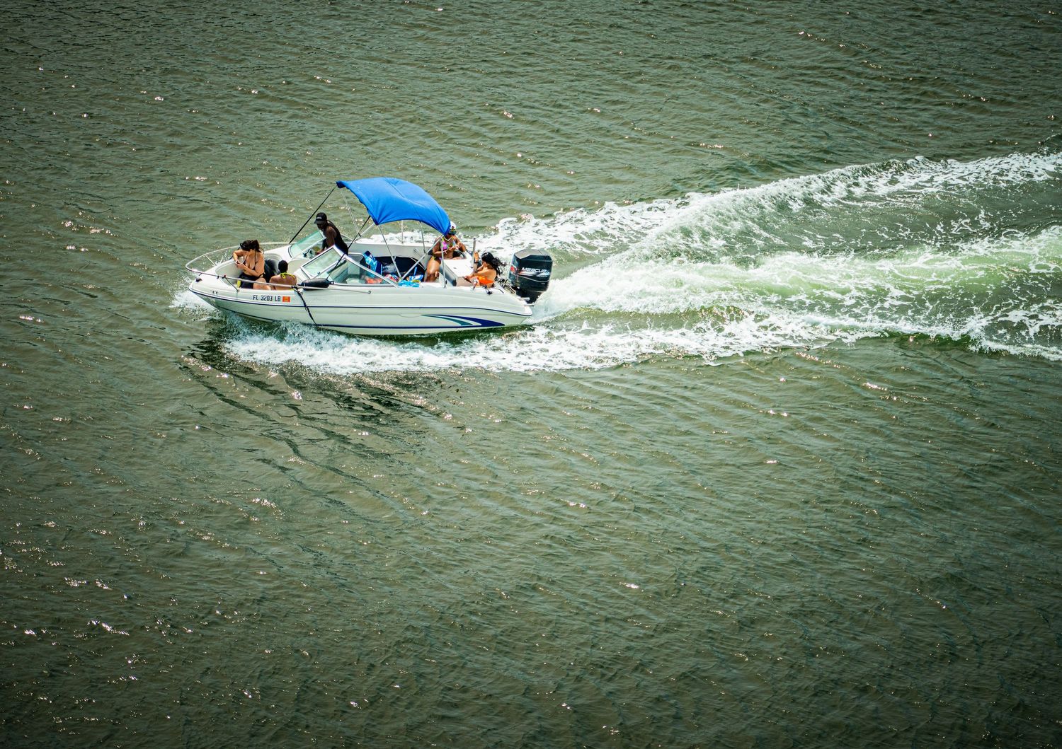Recreational boats creating wakes while moving through green coastal waters.