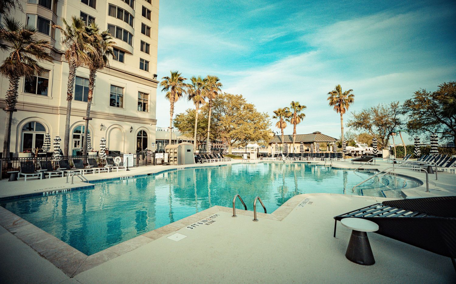 Panoramic collage of luxury beachfront resort showing pool, palm trees, and modern buildings against blue sky.