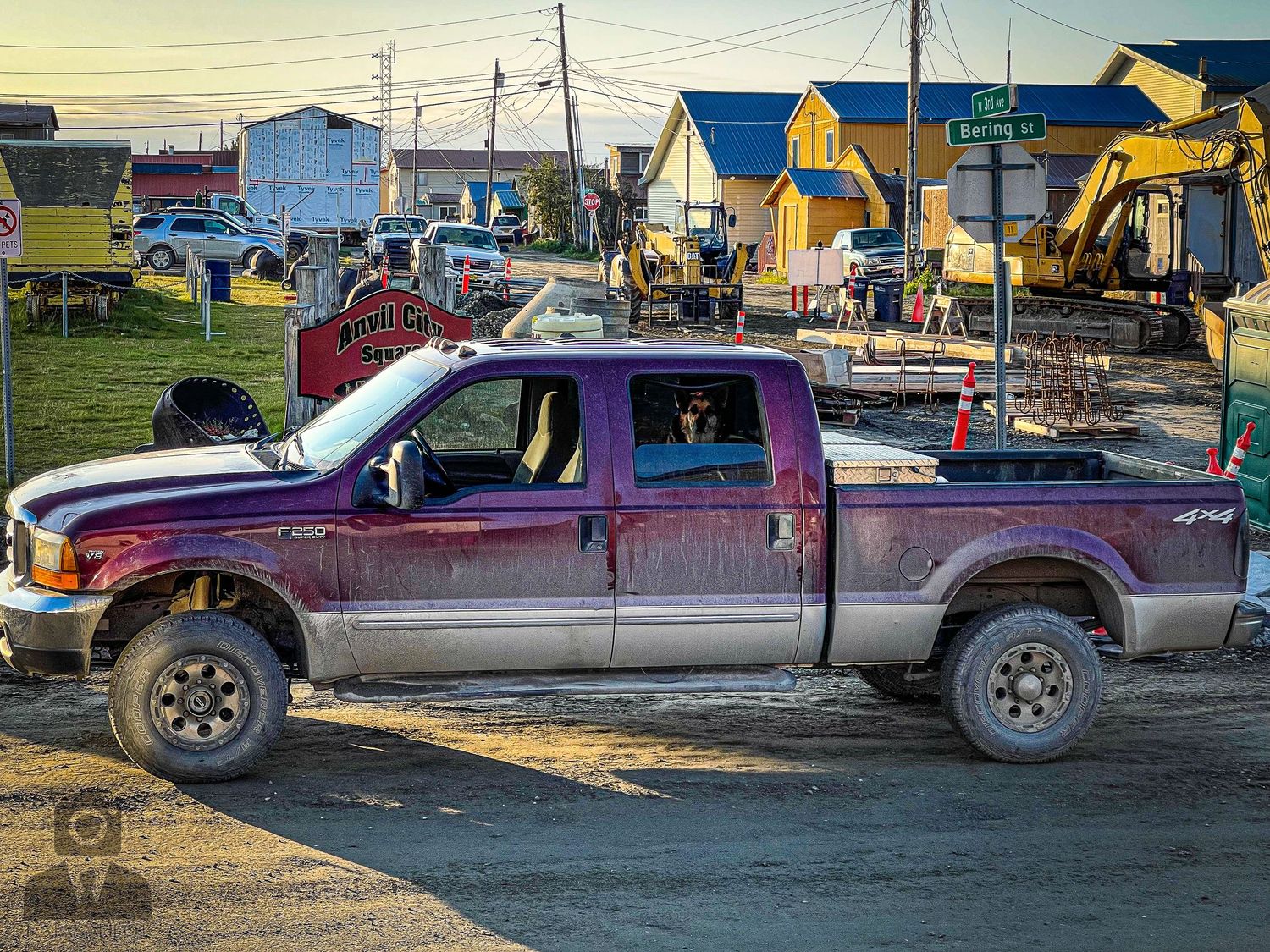 Row of pickup trucks parked in front of colorful buildings in a small town.