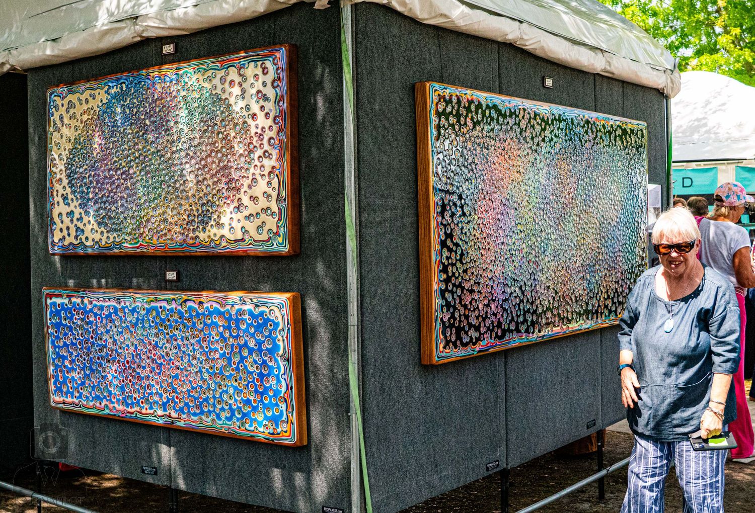 Art gallery wall displaying vibrant paintings with reflective lighting effects.