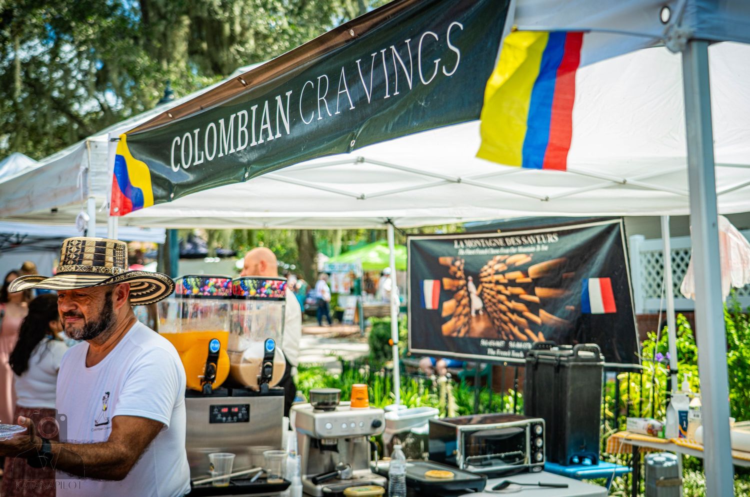 Colombian food vendor stall with colorful flag banner at outdoor market.